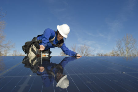 A solar installer fastening a frameless new-technology solar panel to a roof in Colorado.