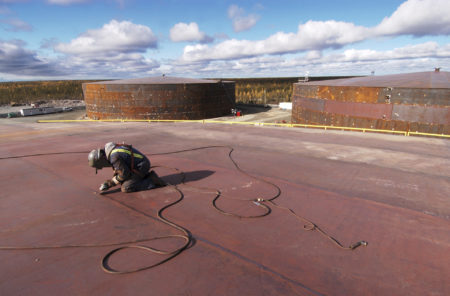 A welder works on the roof a fuel container at a tank farm in Yellowknife, NWT