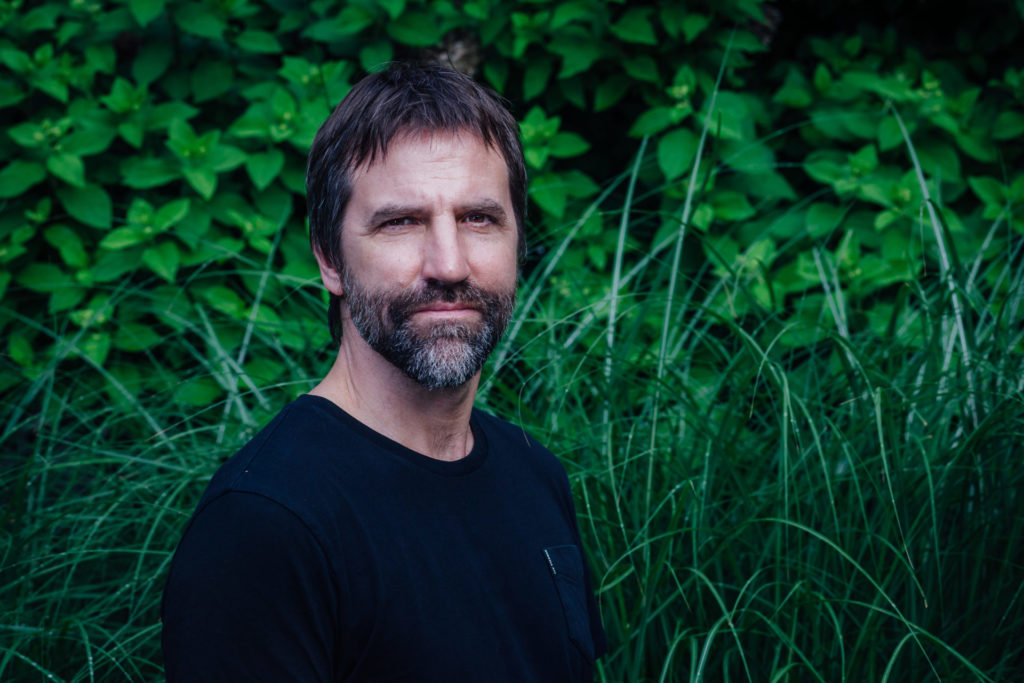 Steven Guilbeault stands in front of foliage. 