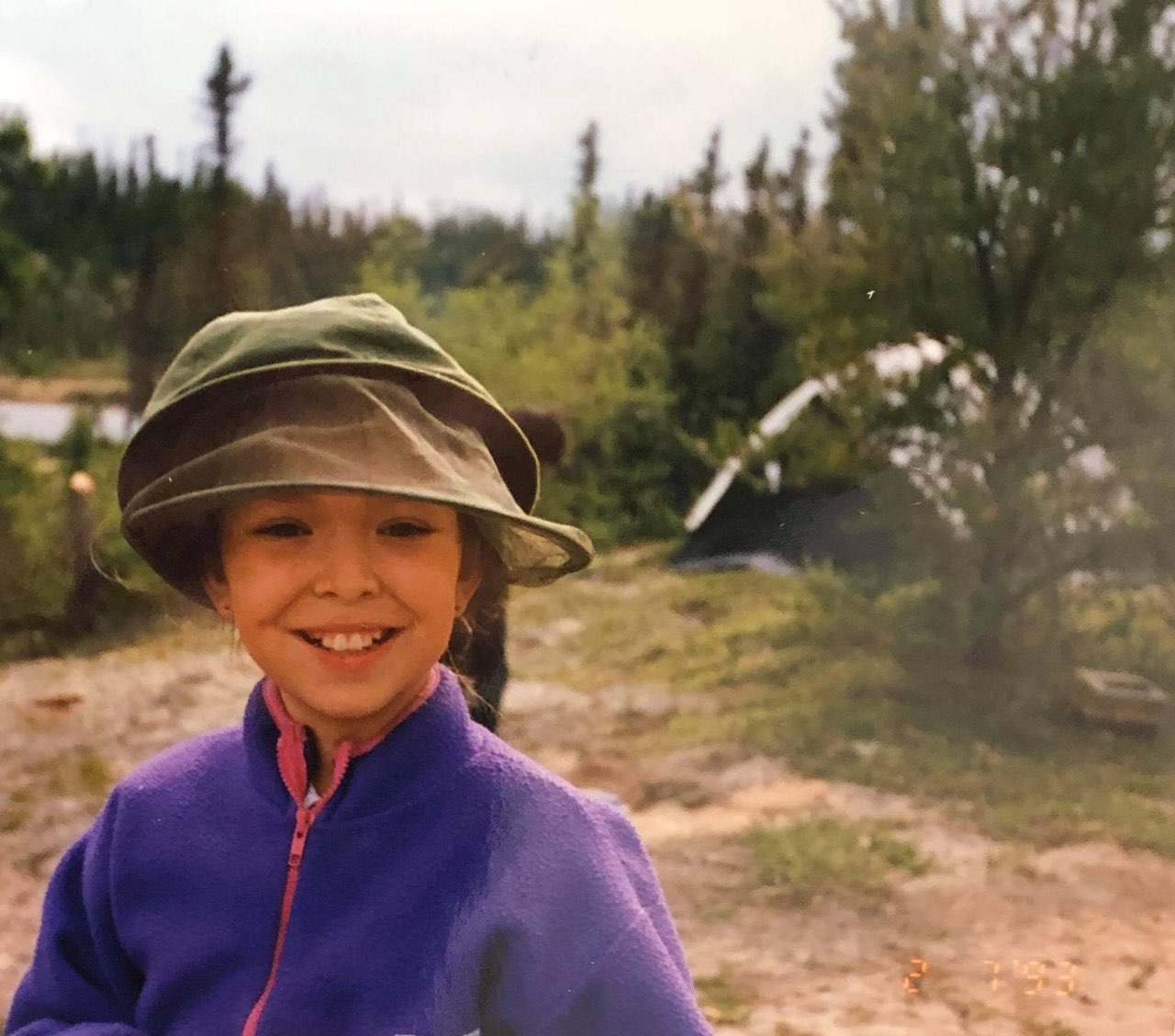 Young Stephanie Thorassie standing outside near a campsite
