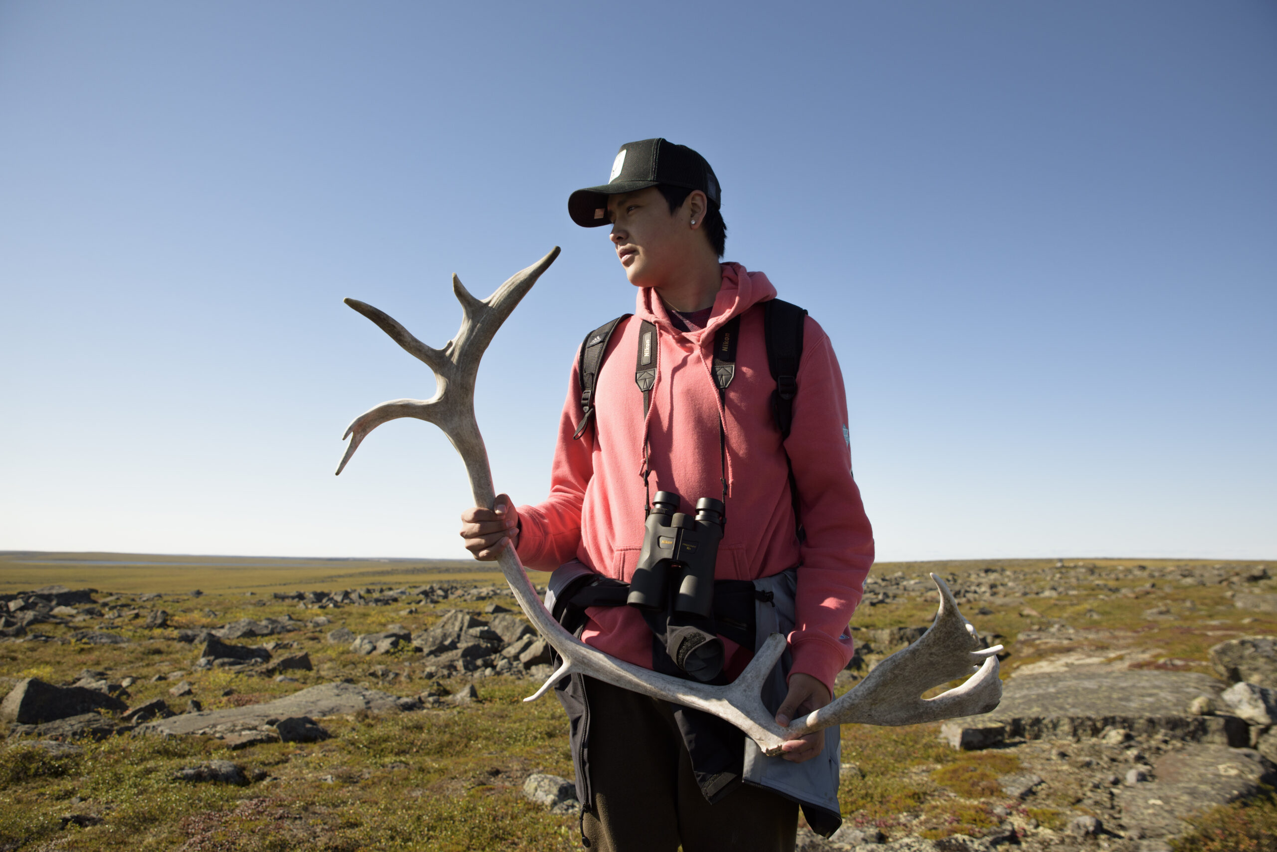Youth researcher Ahri Ekendia holds a caribou antler while scouting the landscape for a herd as part of the Ekwǫ̀ Nàxoède K’è: Boots on the Ground program, which trains youth in research techniques, biology and natural sciences. Photo: Pat Kane / The Narwhal