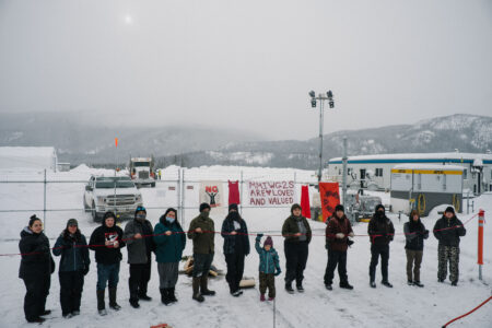 A line of Wet’suwet’en land defenders in front of Coastal GasLink work site holding a red rope
