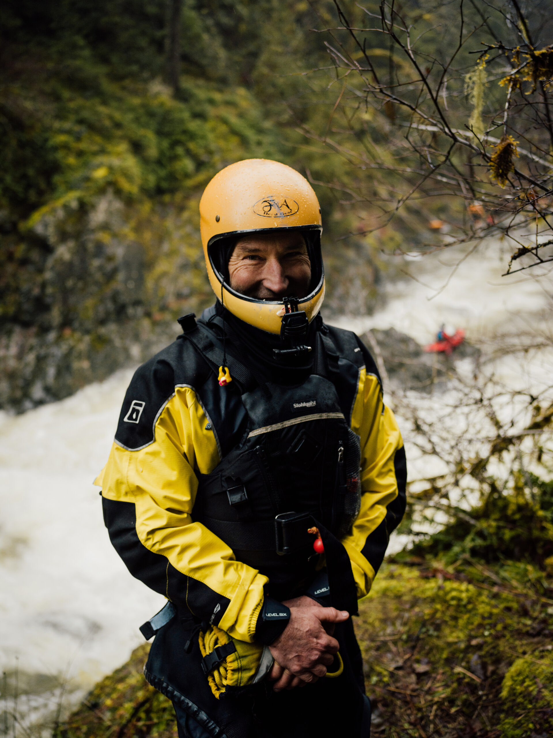 Stephen Hunt, white water kayaker stands by the Koksilah River in a yellow helmet