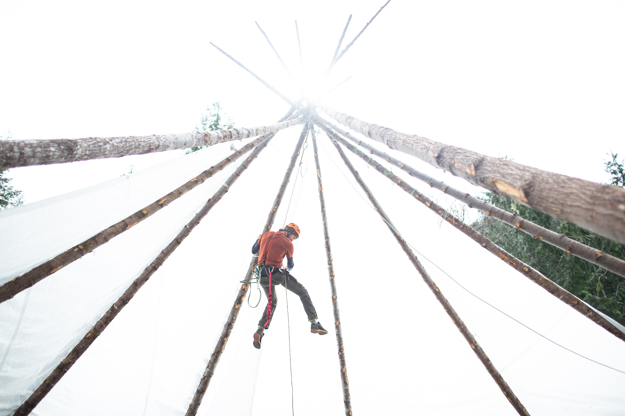 A man rappelling from a wooden tent structure