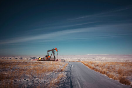 An oil and gas pumpjack beside an empty road