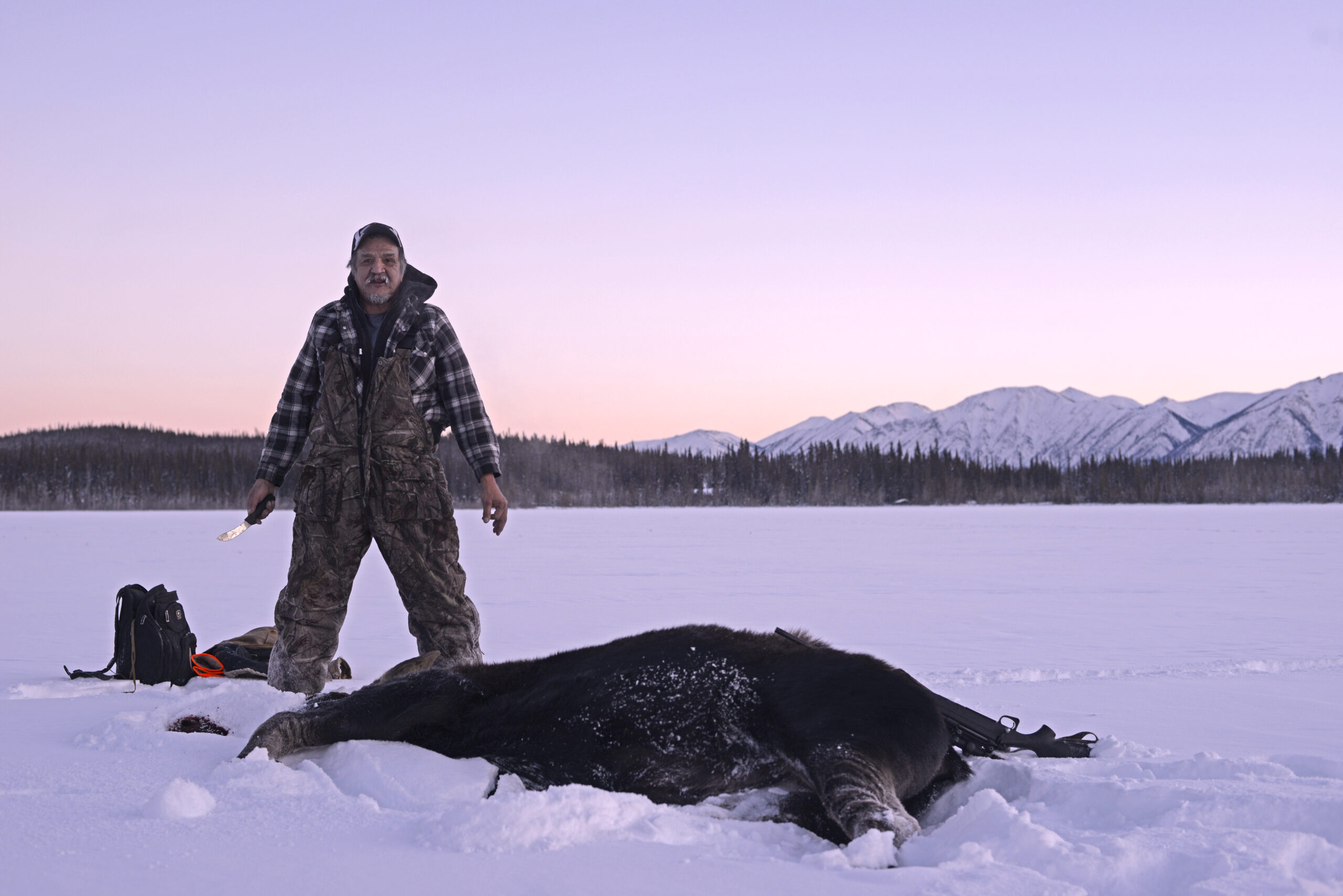 man standing in the snow next to downed animal