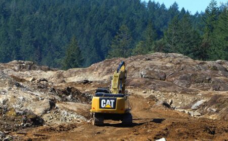 yellow machinery on rocks with green trees in the background