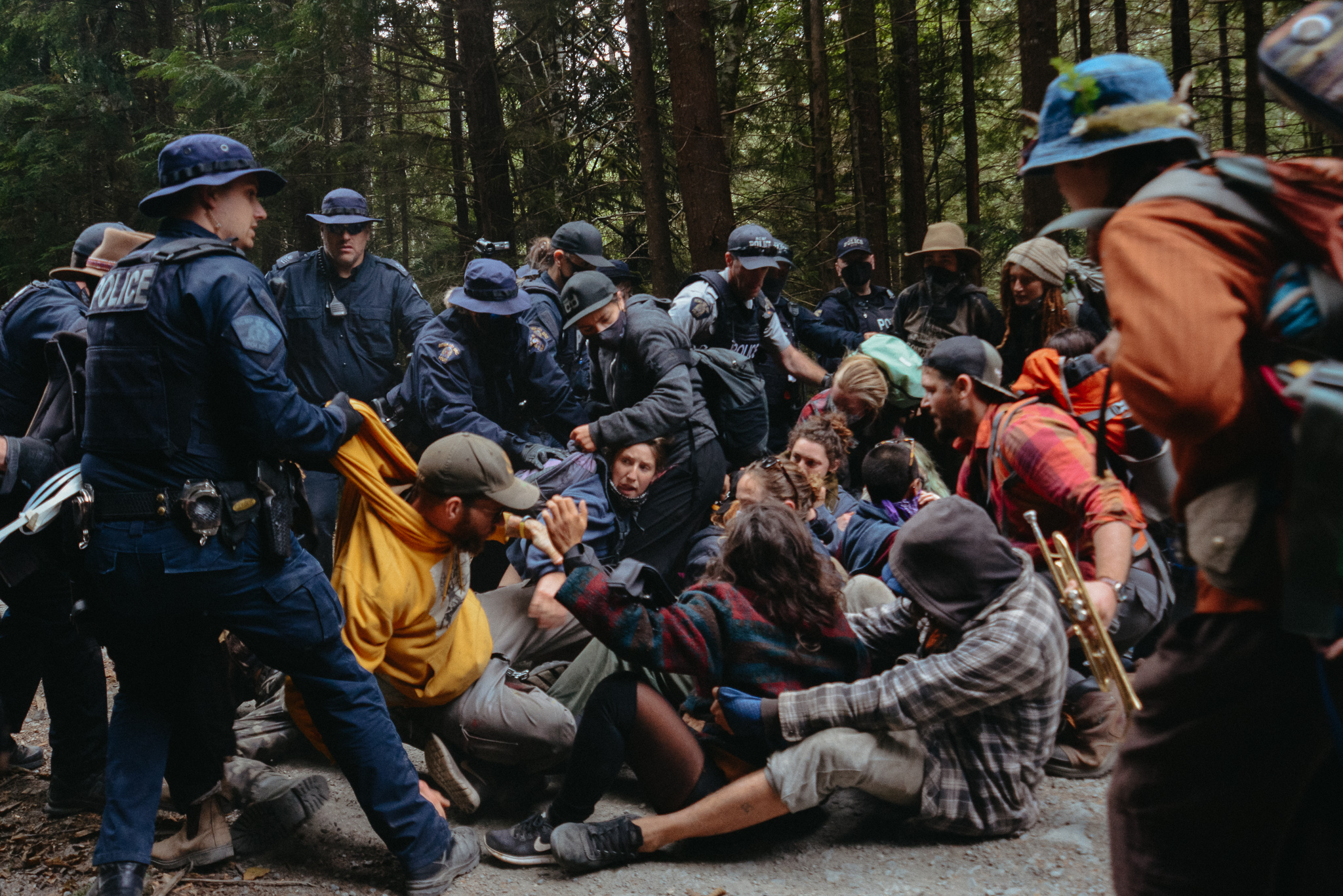 RCMP surrounding a group of protestors on the ground at Fairy Creek