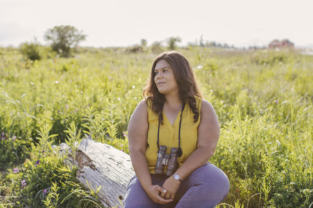Melissa Hafting (she/her) sits down while bird watching in Iona Regional Park in Richmond, B.C.