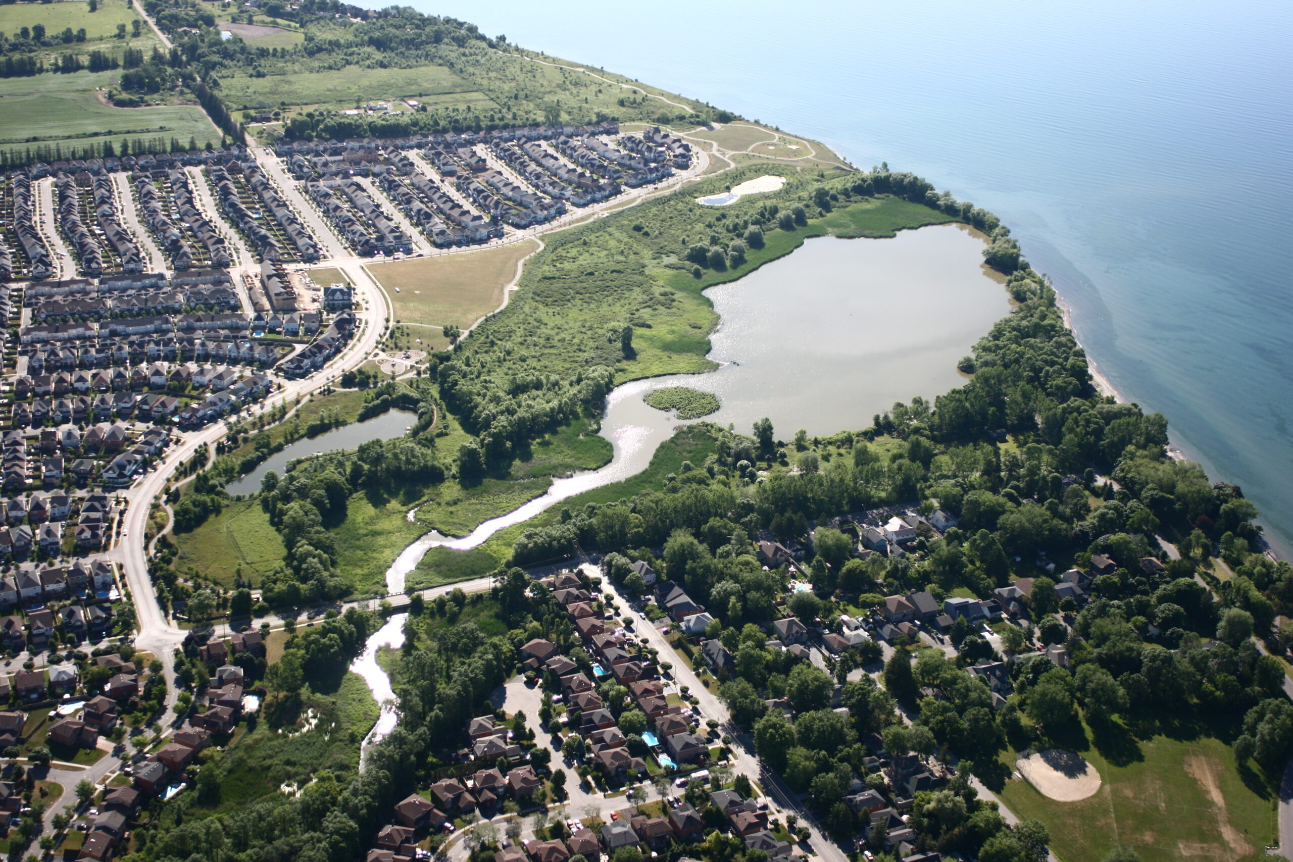 An aerial photo of Carruthers Creek as it passes by homes and drains in Lake Ontario.