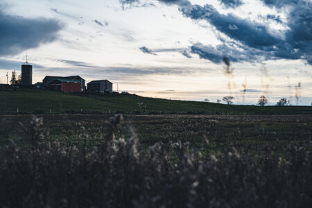A view of a farm sitting on a hill at sunset