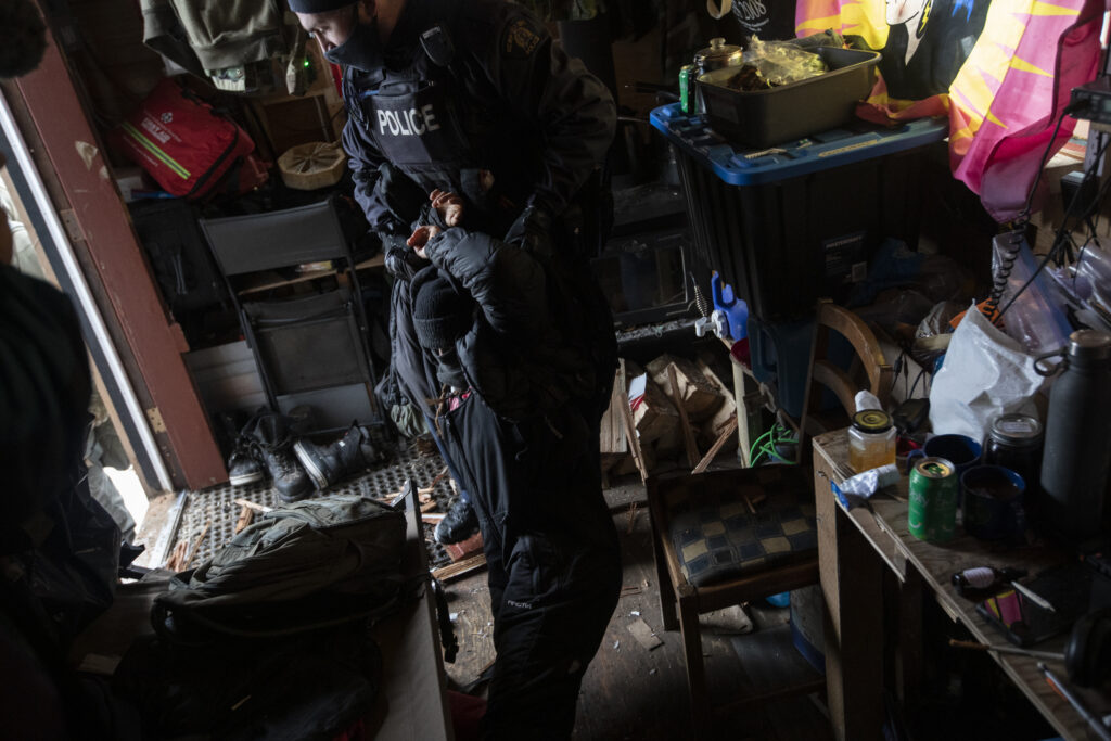 An RCMP officer drags a woman in a small one-room cabin in Gidimt'en territory