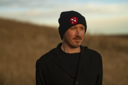 Drew Anderson of The Narwhal standing in a grassy field