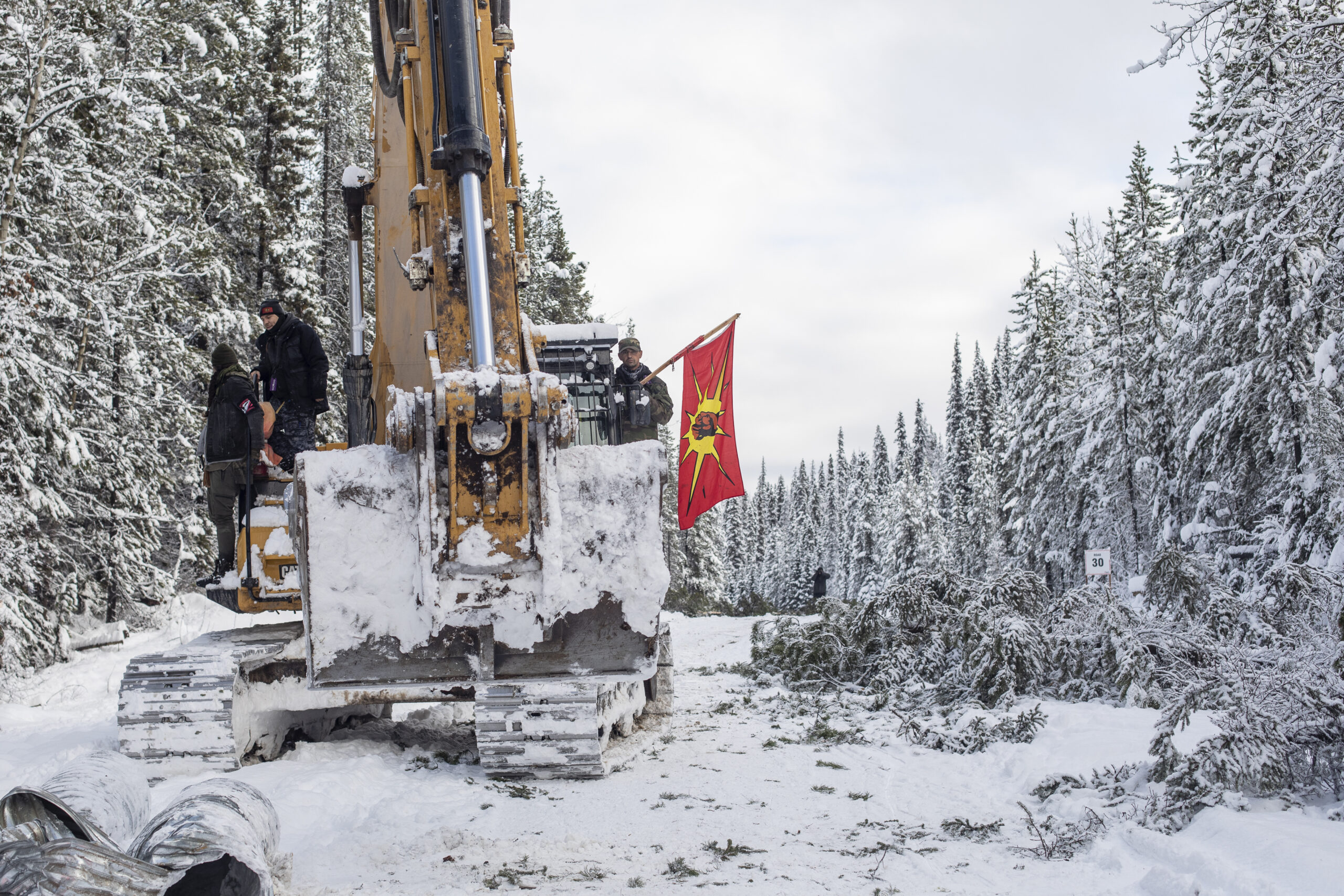 Wet'suwet'en land defenders blockade a snowy road with Coastal GasLink excavator