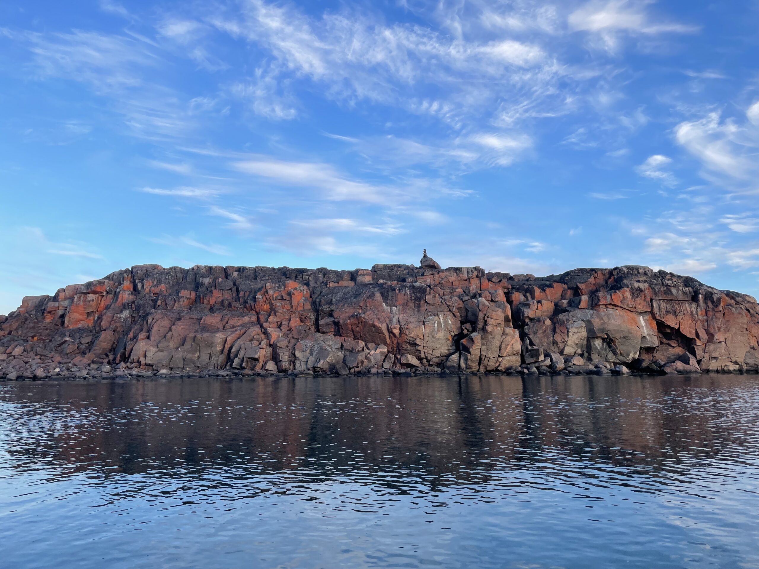 Red-tinged cliffs along the shore in Aviqtuuq; Taloyoak, Nunavut