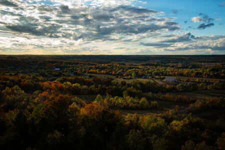 Trees and farmland are seen from above from Mount Nemo in Halton Region just after sunset, with moody lighting.