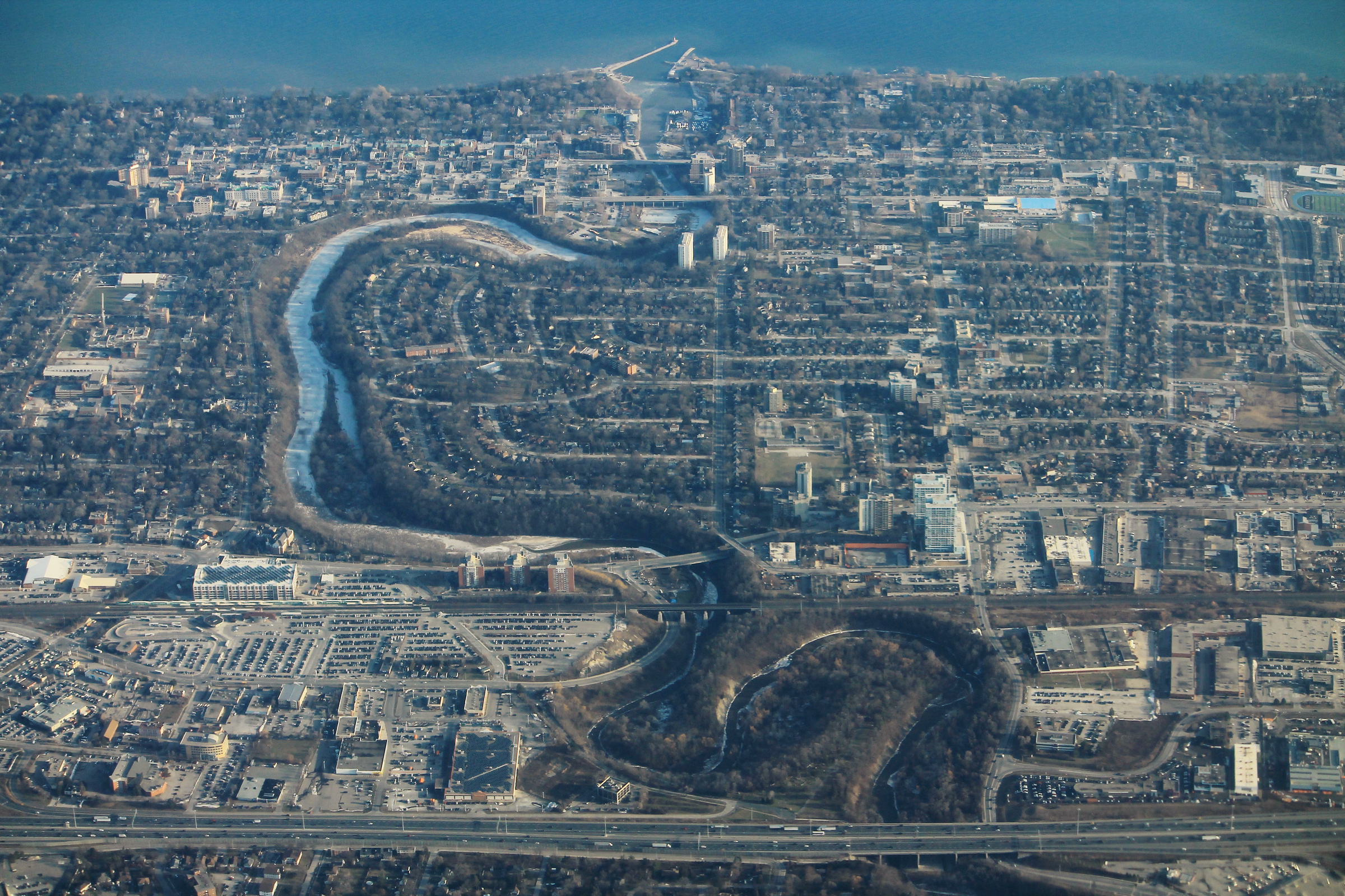 Oakville is seen from above, with a creek winding through dense suburbs into Lake Ontario.