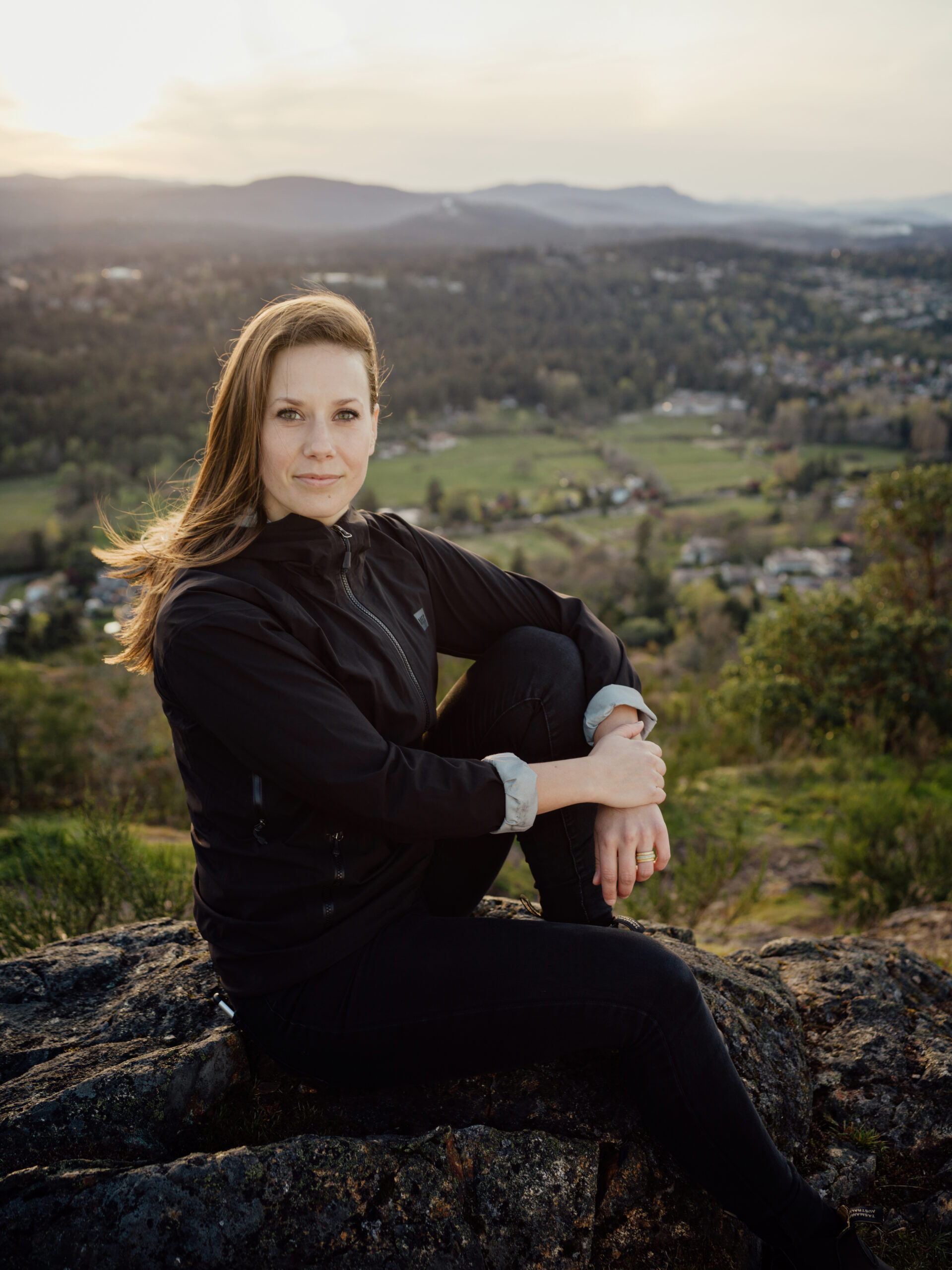 A woman in a black jacket sitting on a rocky outcrop