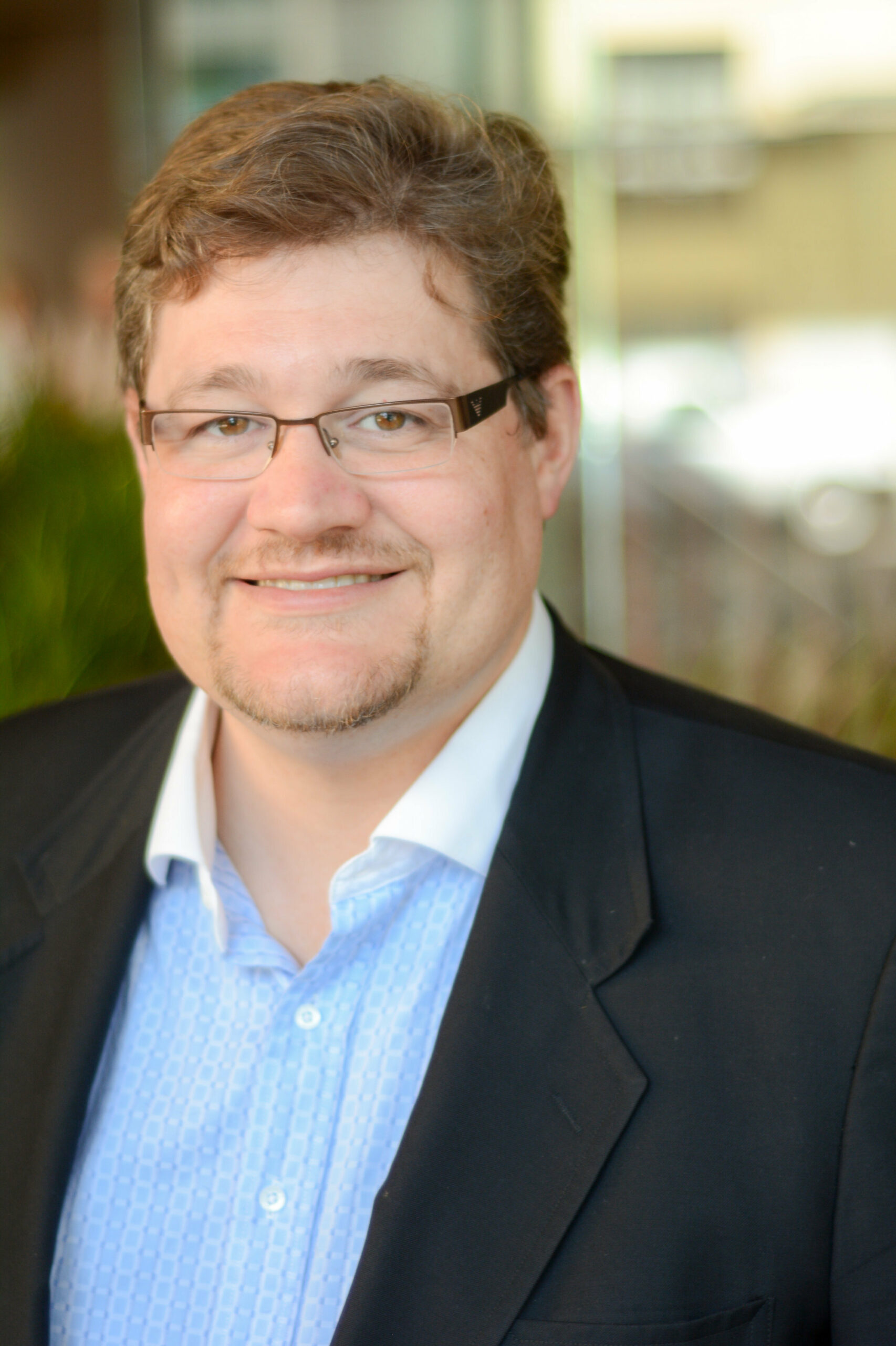 Man in suit jacket smiling: Geordie Hungerford Gwich’in Nation