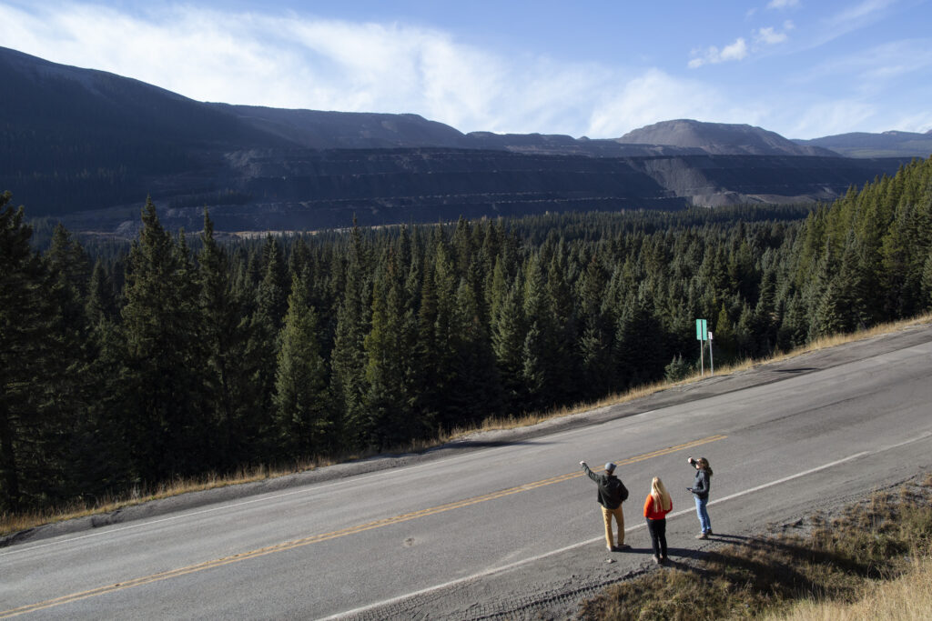 Three people stand on a highway looking out over a Teck Resource's coal mine