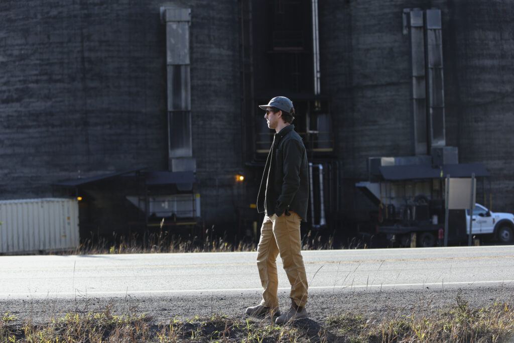 A man in a grey jacket stands near Teck Resources' coal train loading operations