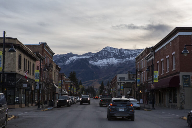 A small town city street with snowy mountains in the distance