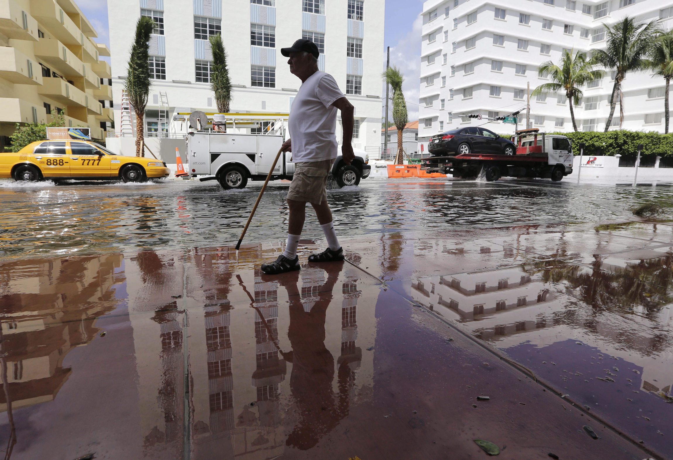 A man with a cane walks along a flooded street in Miami Beach in 2015