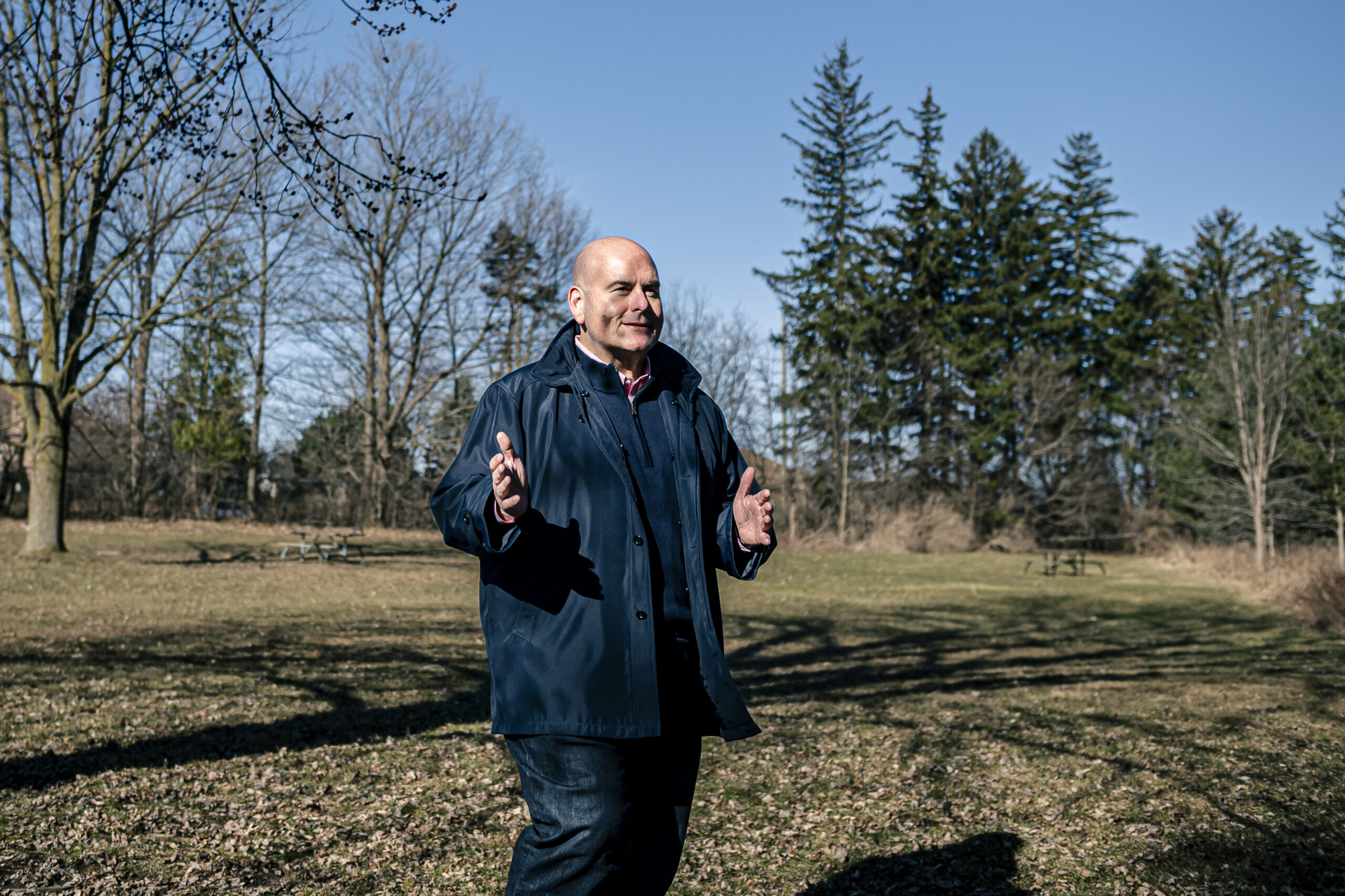 Ontario Liberal leader Steven Del Duca walks in the middle of a field with trees in the background on a sunny early spring day, gesturing with his hands, in the lead-up to the 2022 Ontario election.