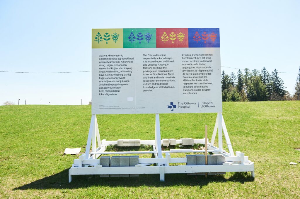 A wooden sign in a green grass field with a land acknowledgement stated on it.