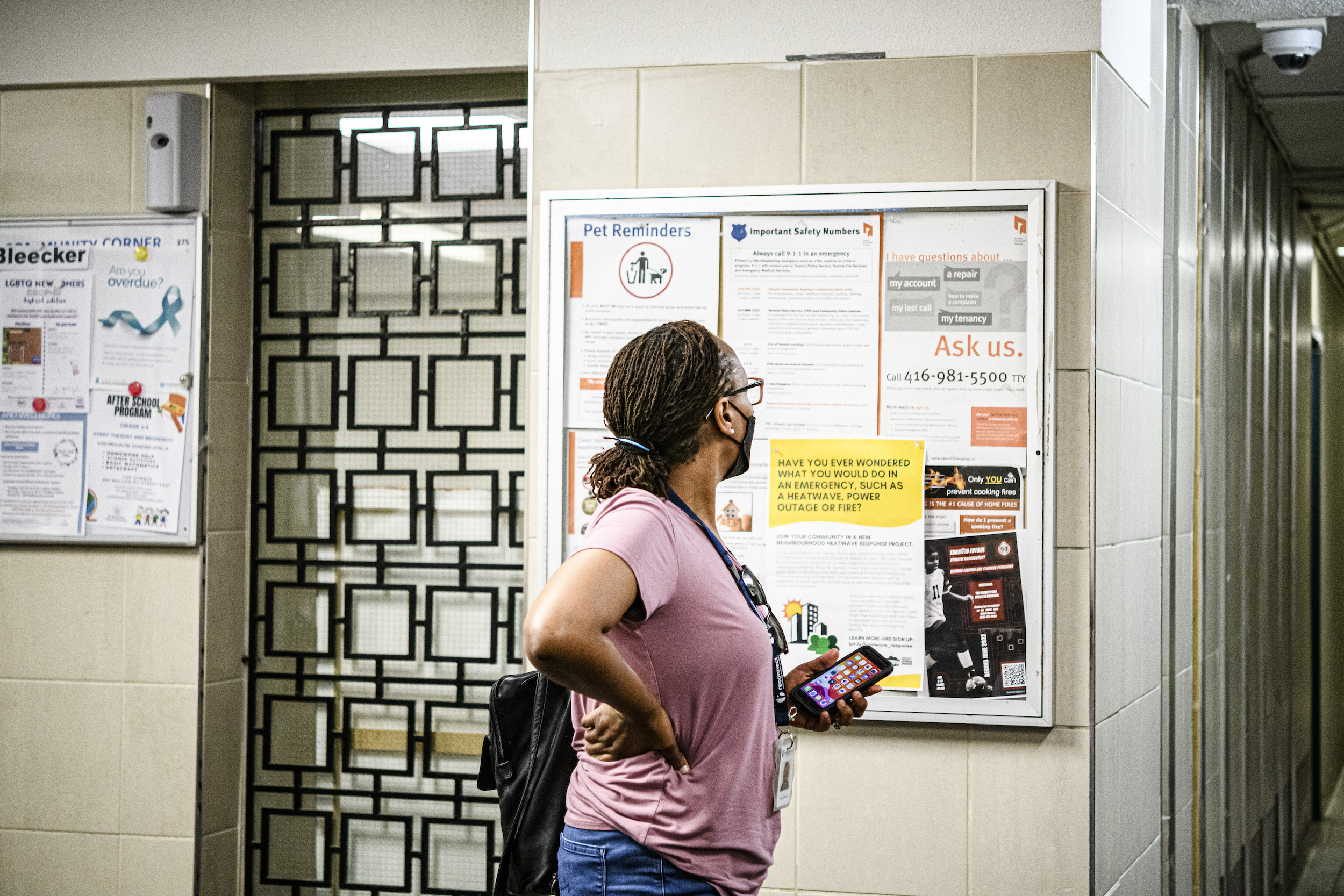 A resident of St. James Town reads a pamphlet from the Community Resilience to Extreme Weather (CREW), posted in the building lobby of an apartment building in St. James Town, Toronto.