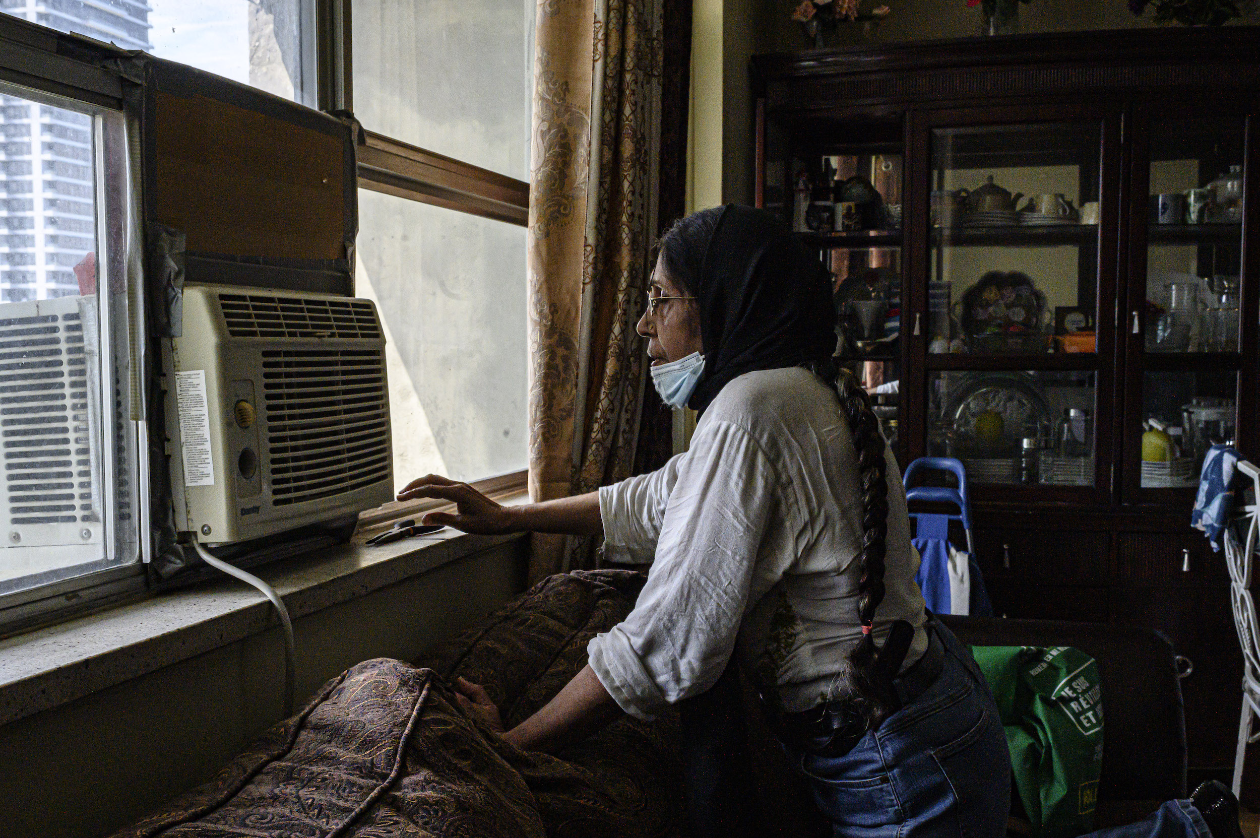 Shaheen Kausar, volunteer with Community Resilience to Extreme Weather (CREW), and resident of St. James Town, Toronto, turns on the air conditioner in her unit.