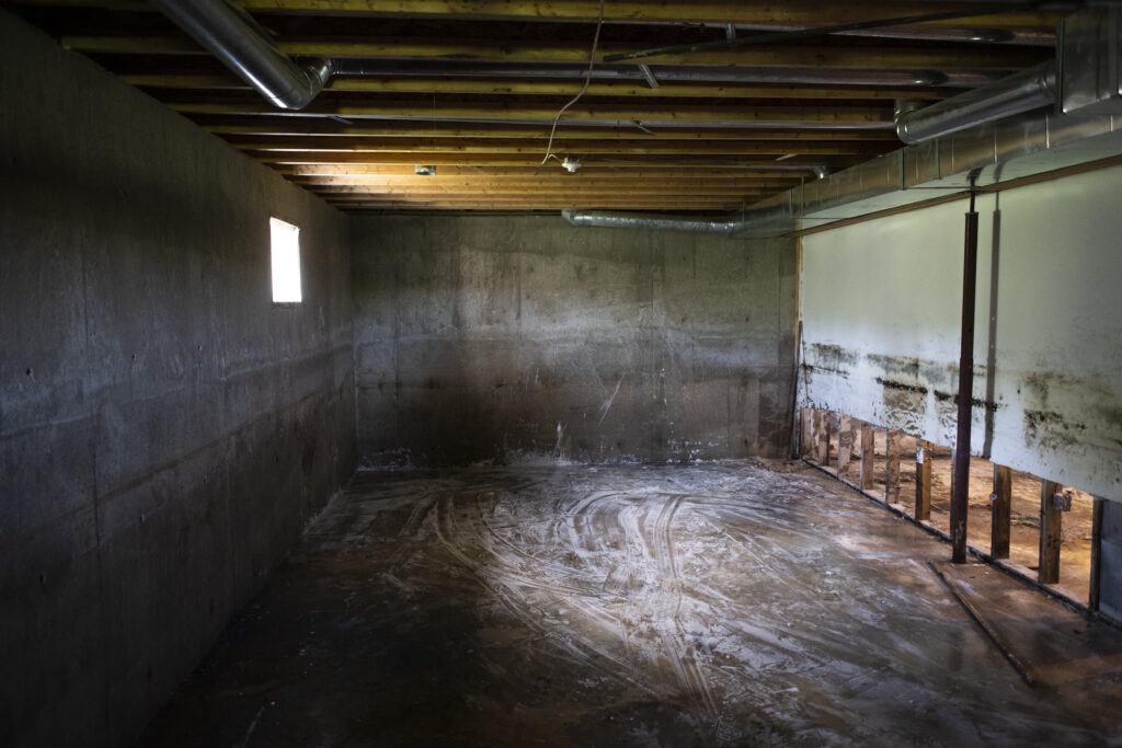 An empty basement room in Peguis First Nation with bleach and mold on the concrete floor and walls after the flood