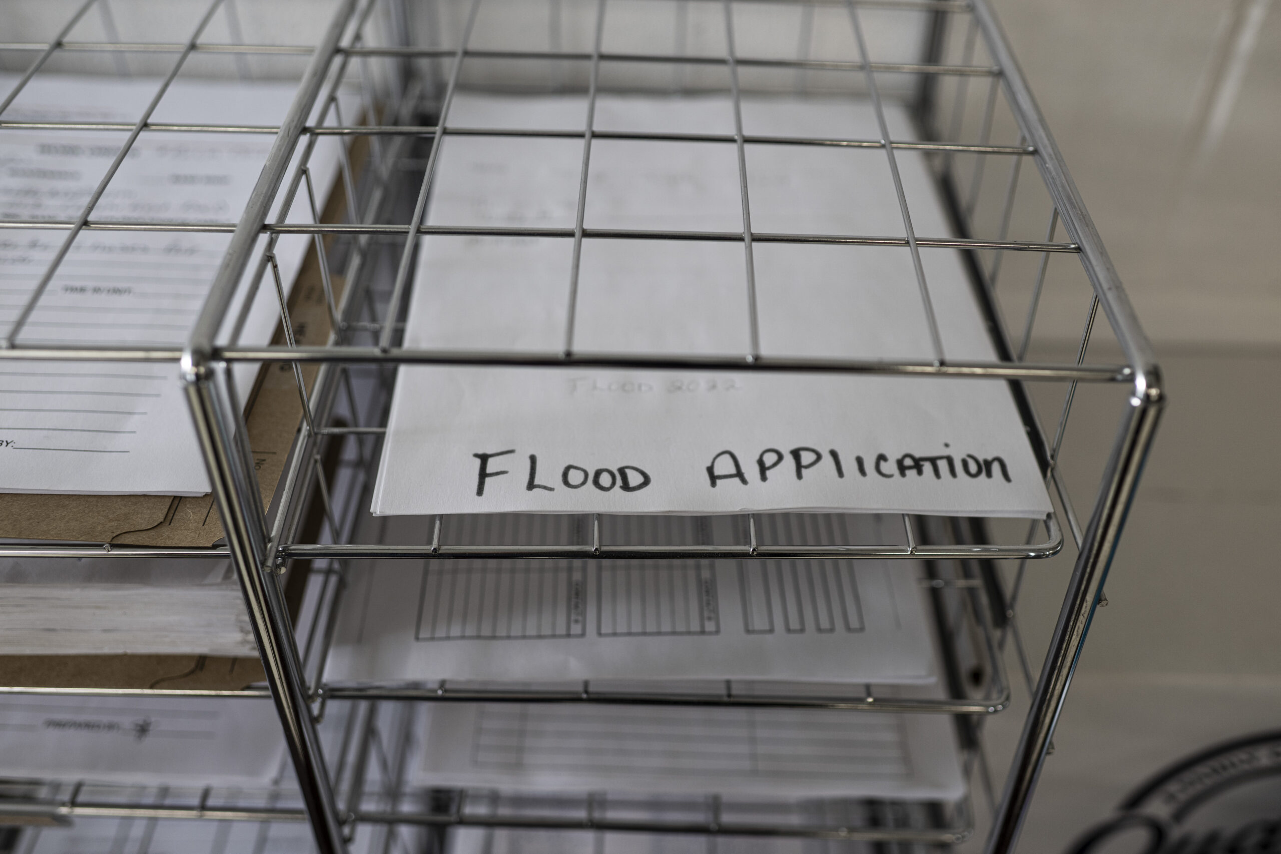 a piece of paper reading 'flood application' sits in a wire rack