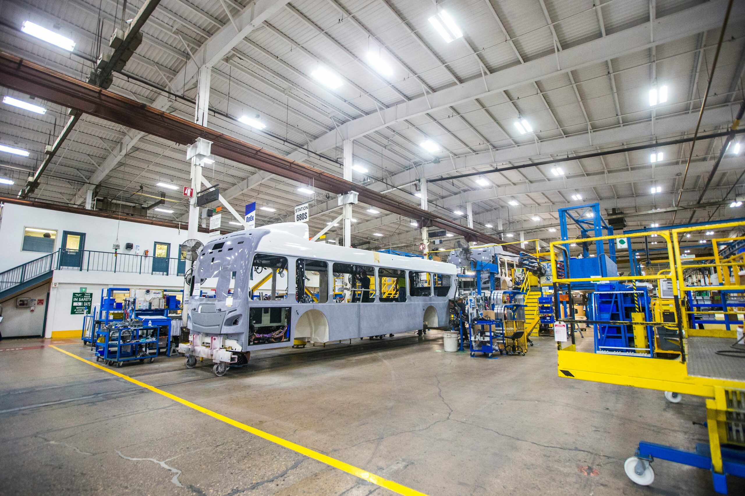Inside electric bus manufacturer New Flyer's Winnipeg plant an incomplete grey bus shell is being fitted with parts