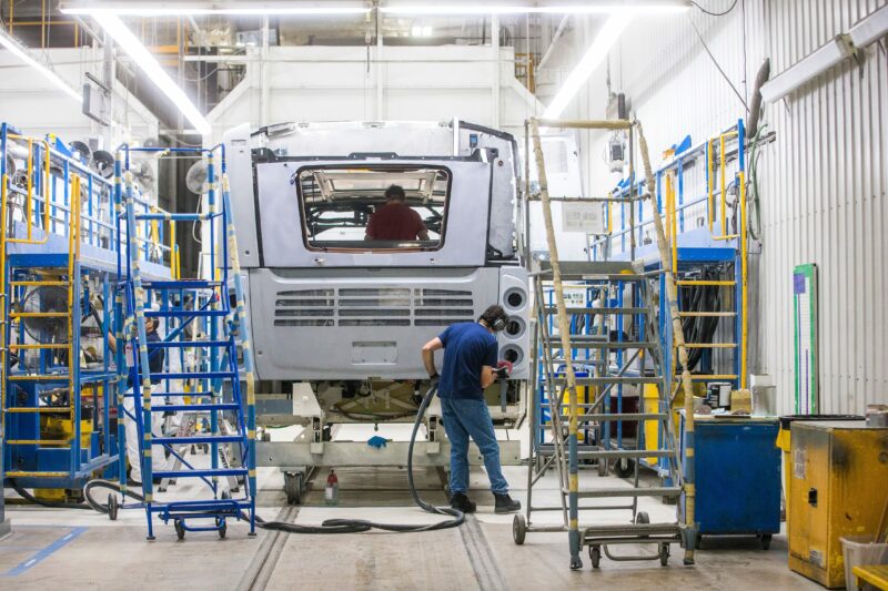 Three New Flyer employees work on the rear of a partially-completed bus shell at the Winnipeg factory
