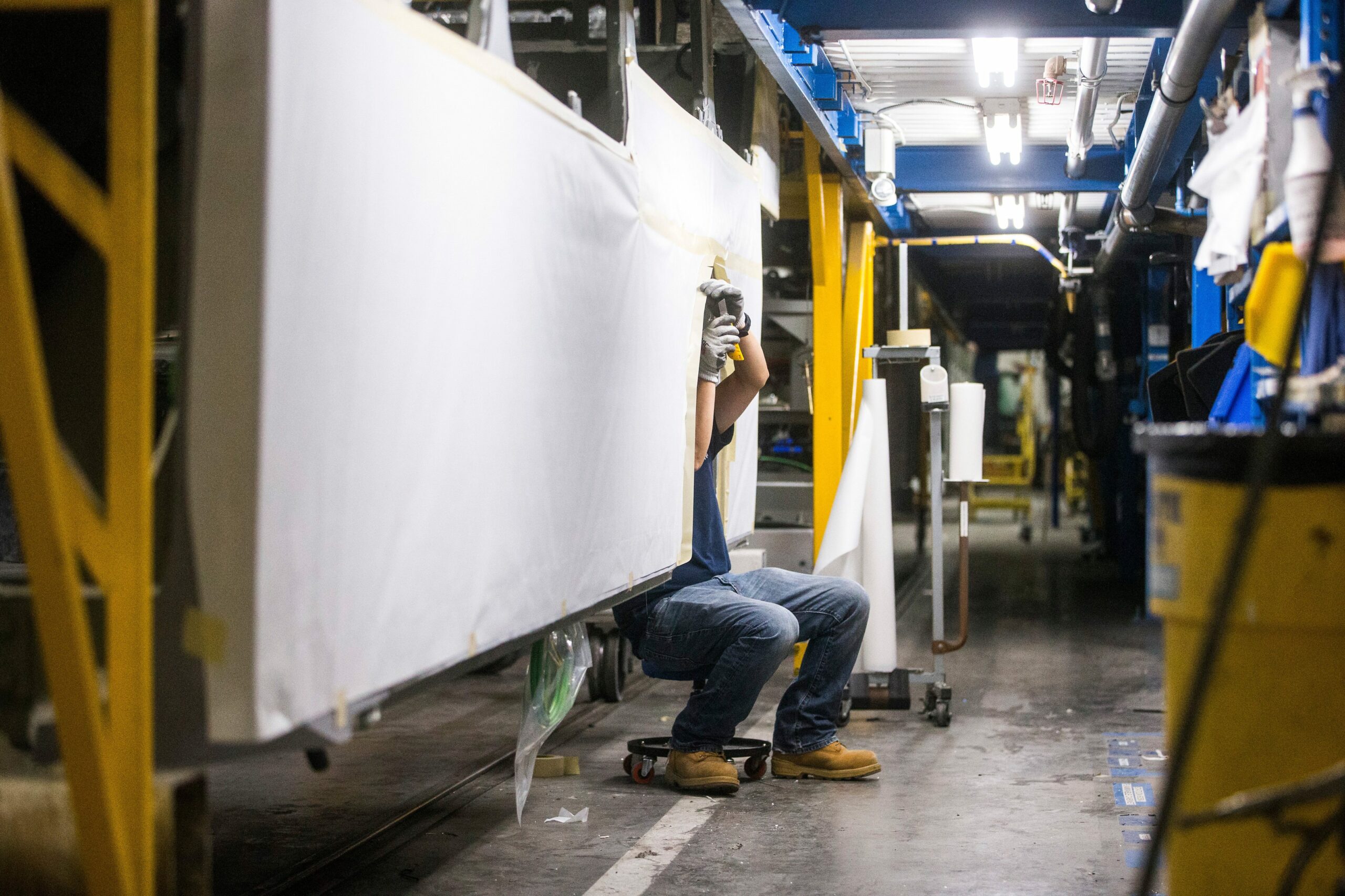 In electric bus maker New Flyer's production facility, a staff member sits below a bus shell he is working on