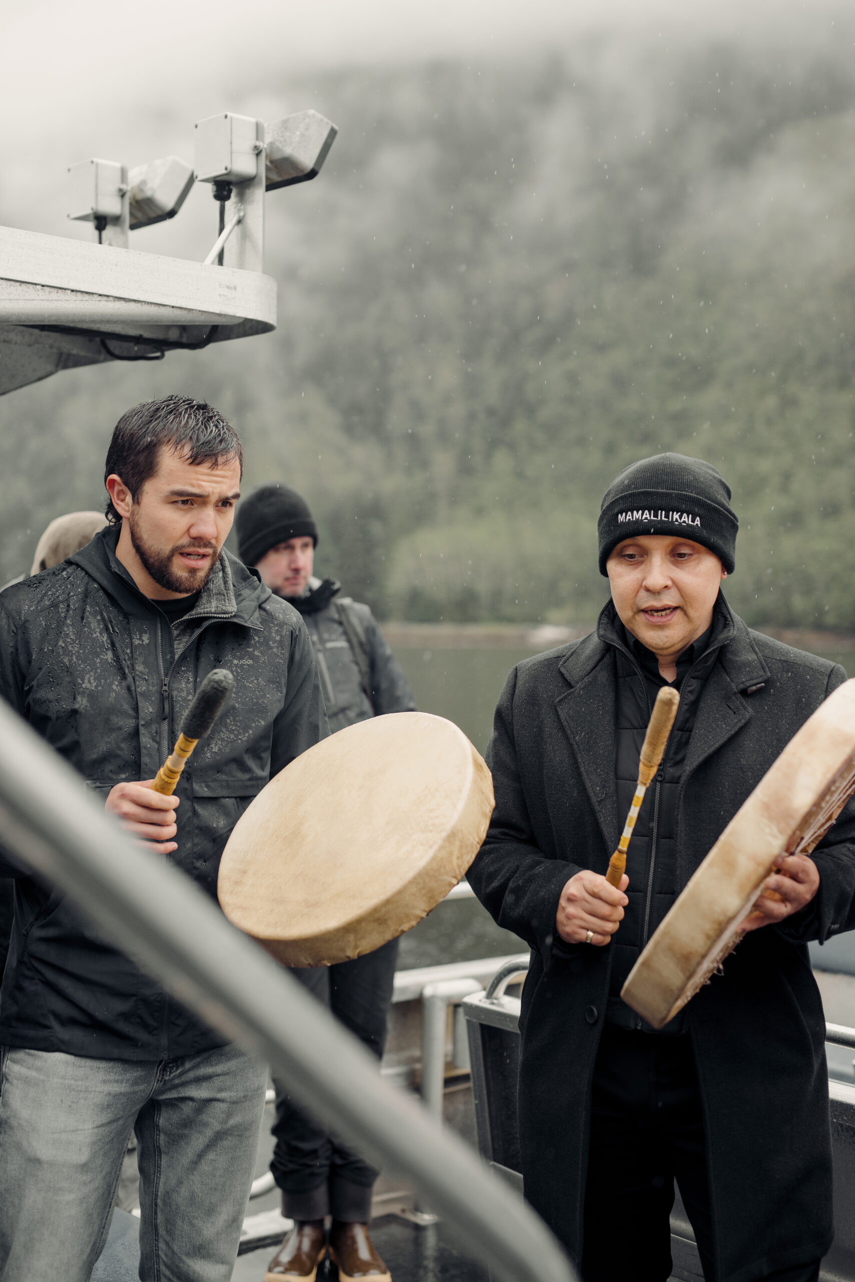 Sasha Perron (left) and Kevin Cranmer drum visitors into the Mamalilikulla’s IPCA dedication ceremony as people disembark from the boat.