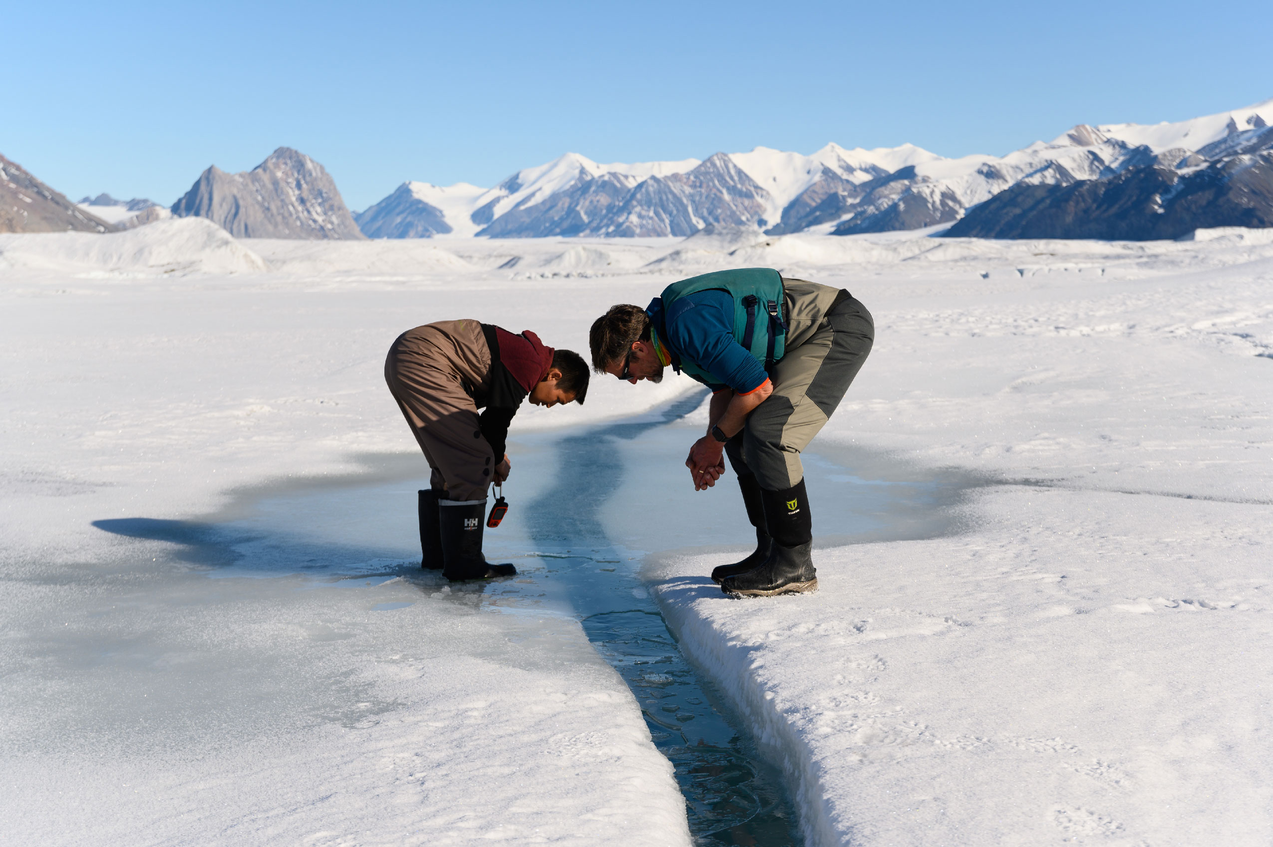 Joseph Shoapik, a resident of Grise Fiord, Nvt., peers down into a crack in the ice alongside Alex Forrest, a limnologist at the University of California, Davis. Just below this ice, a thin layer of freshwater used to float on top of the seawater in what’s known as an epishelf lake — the last of its kind in Canada. 