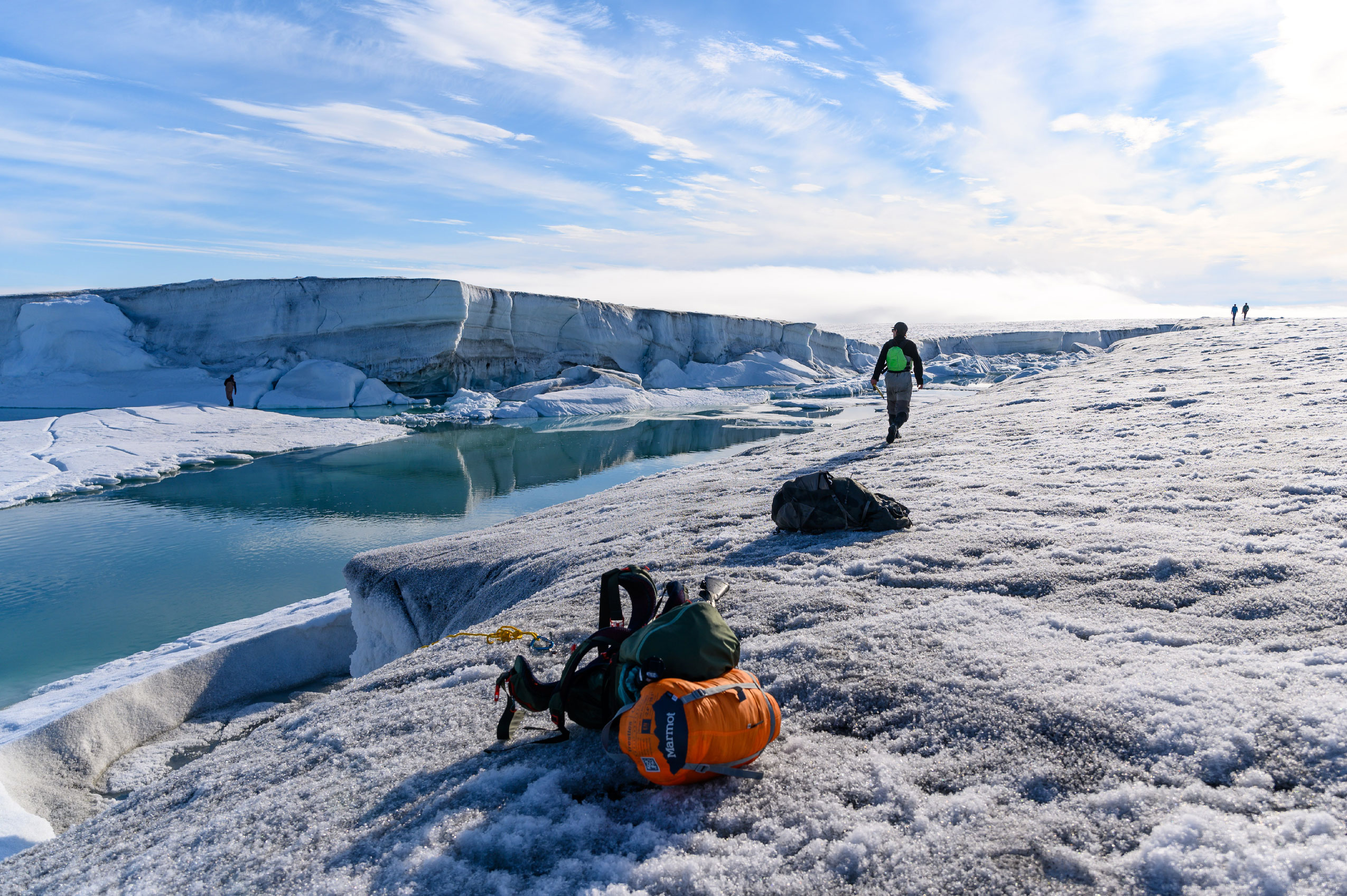 A team scouts for a location to do a conductivity, temperature and depth cast in a channel on the ice shelf. Backpacks and supplies are on the ice.