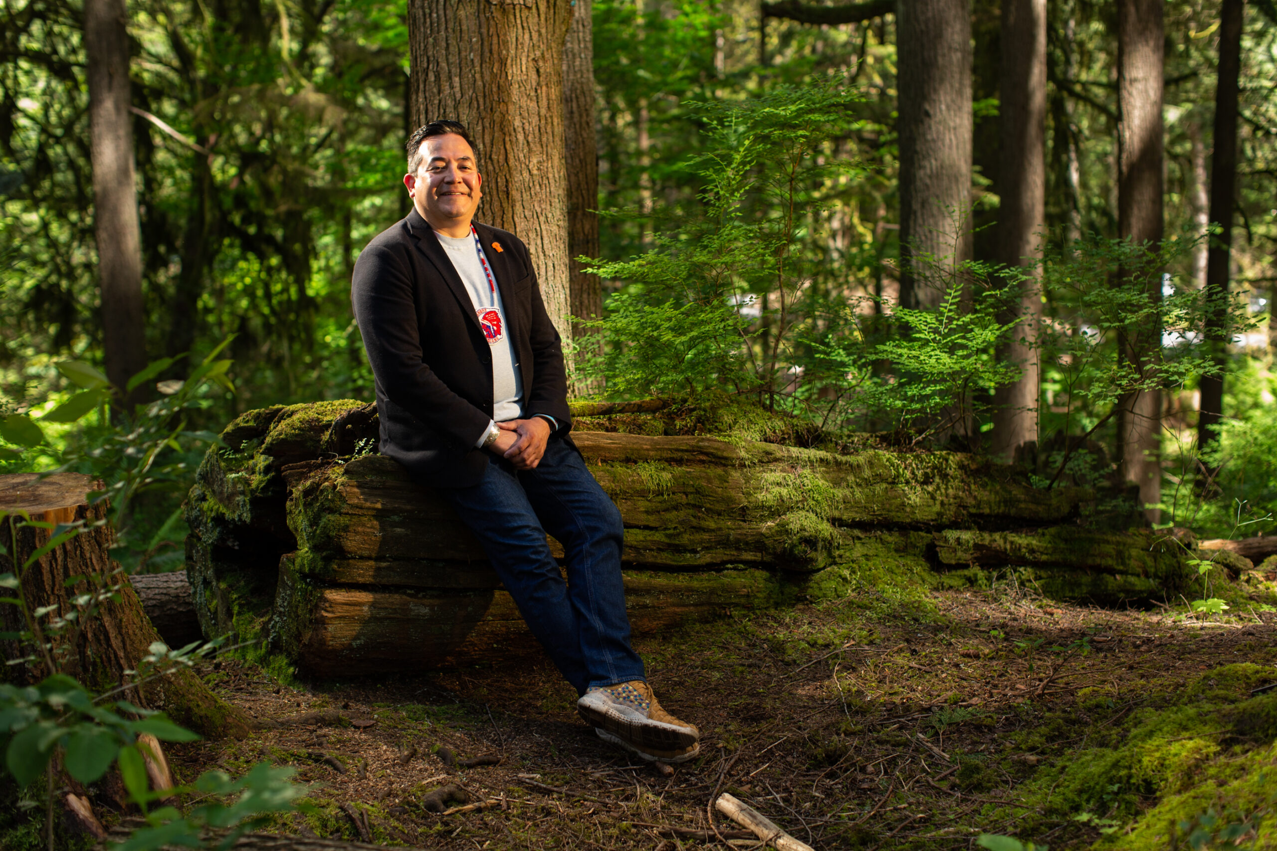 Wilson Williams, spokesperson for Squamish Nation, sitting on a log in the forest