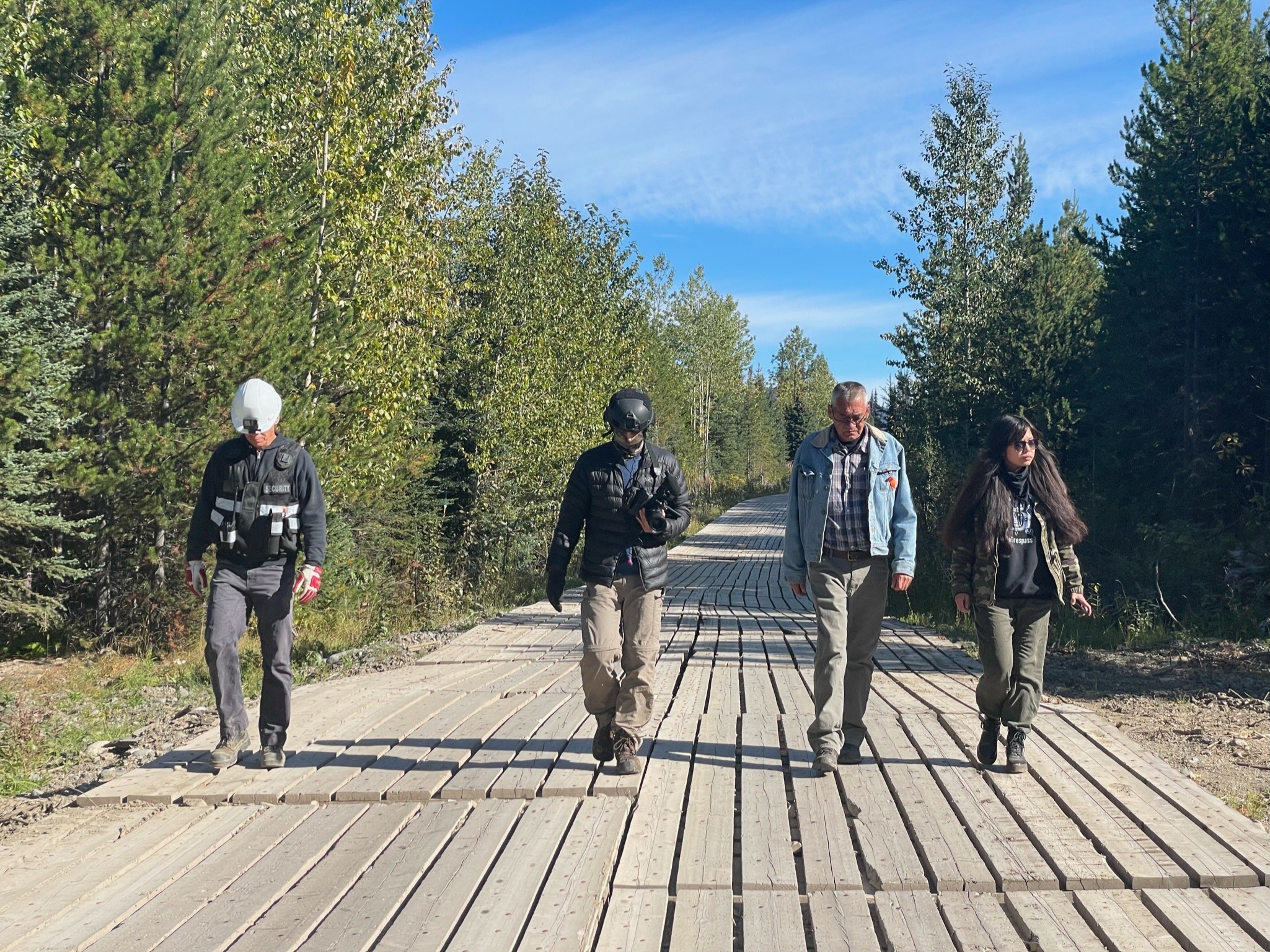 Hereditary Chief Namox walks with Jocey Alec, daughter of Gidimt’en Clan Hereditary Chief Woos along with Coastal GasLink security guards to view Coastal GasLink drilling under the Wedzin Kwa (Morice River)