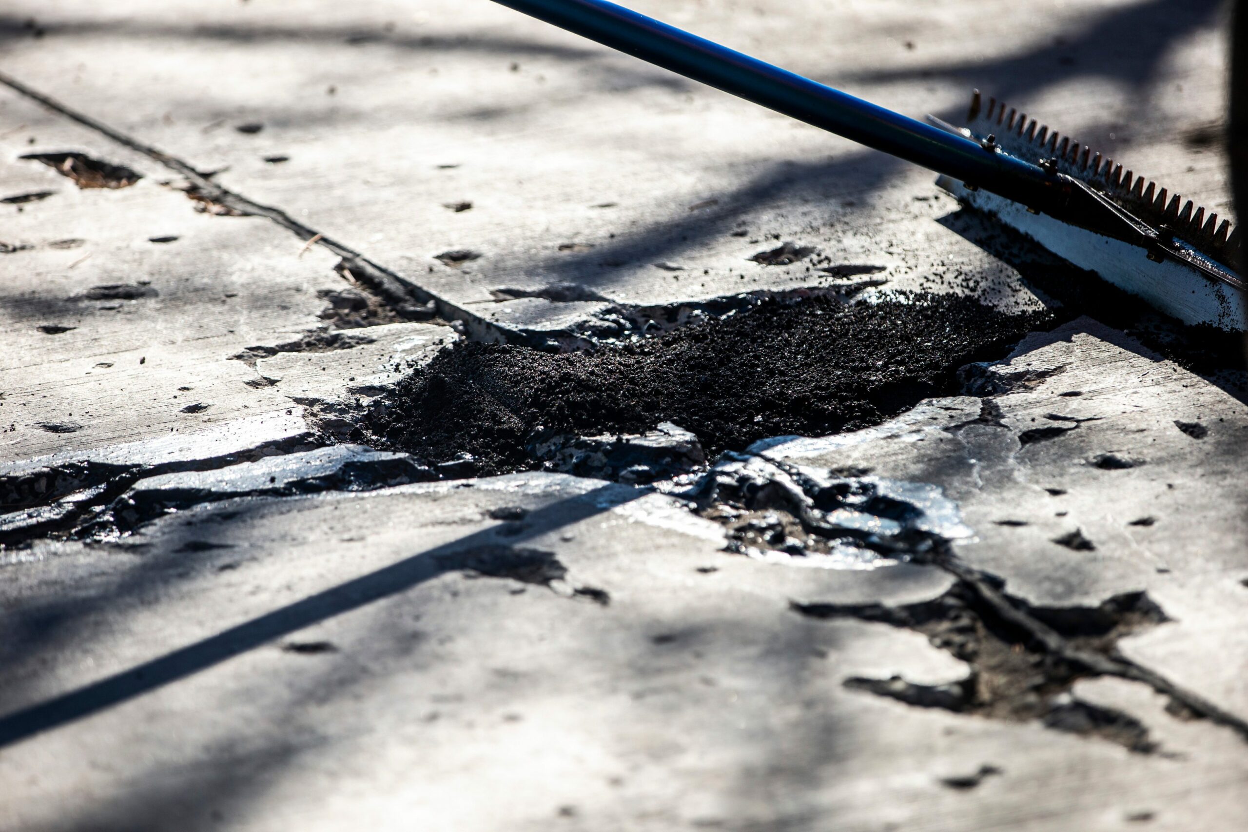 A pothole on a Winnipeg street is partially filled with asphalt during a repair