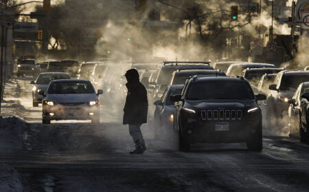 One person is silhouetted against the lights and exhaust from several cars in Winnipeg traffic