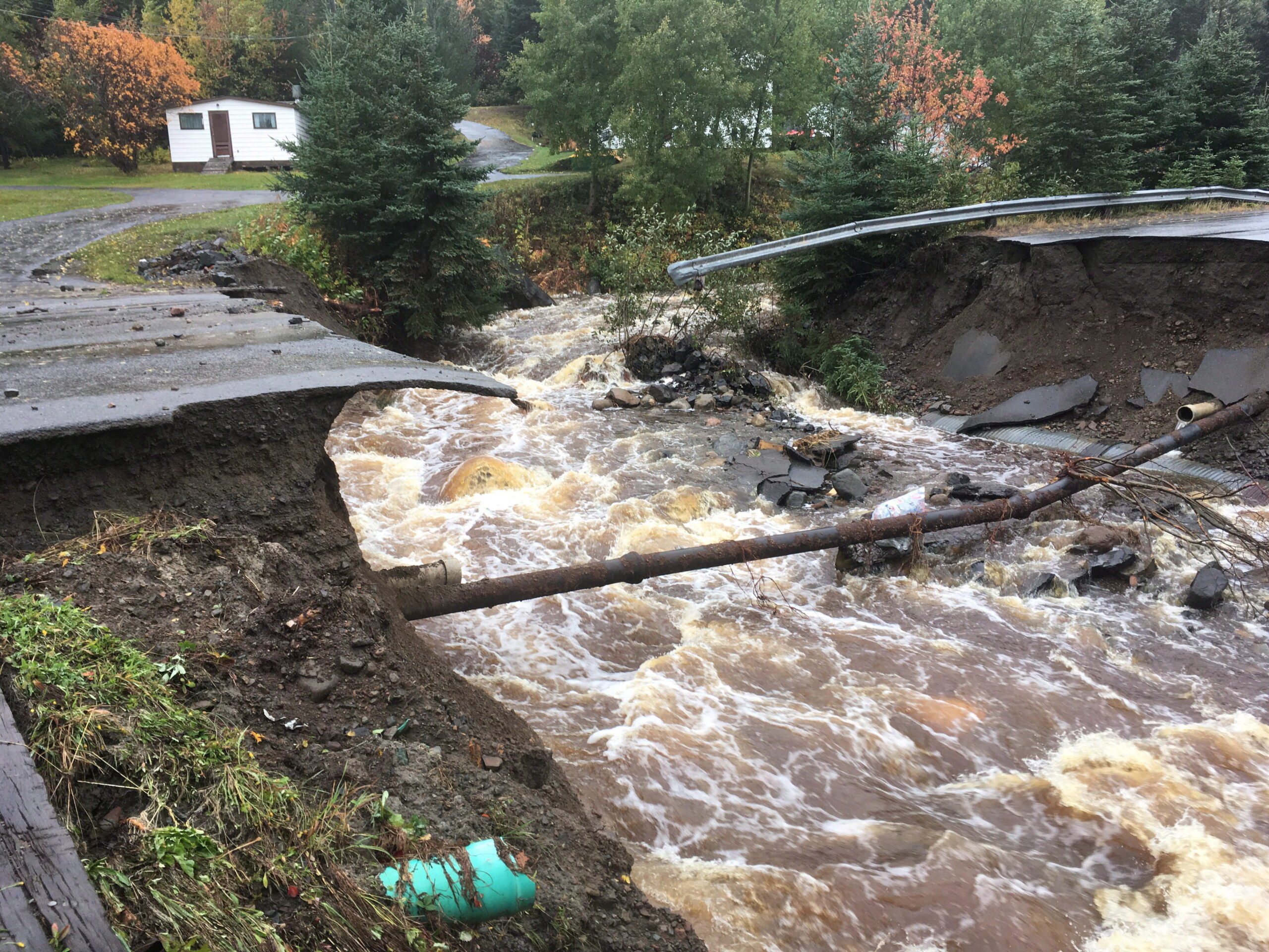 Water rushes under a section of damaged road in Norris Arm, Newfoundland after a hurricane struck in 2016