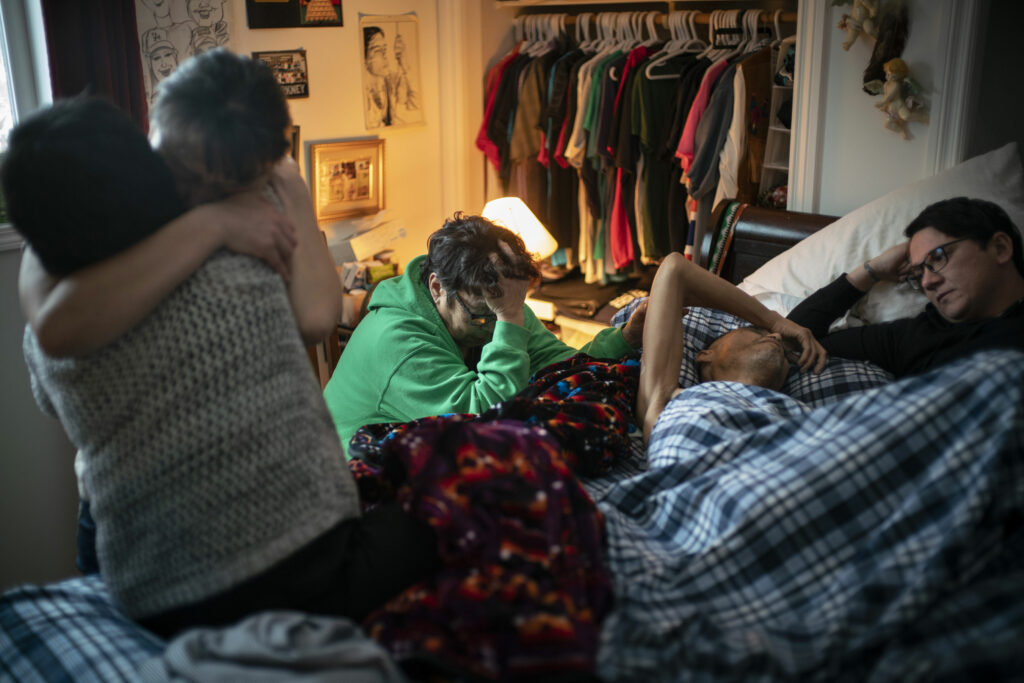 A dying man surrounded by friends and family in a bedroom