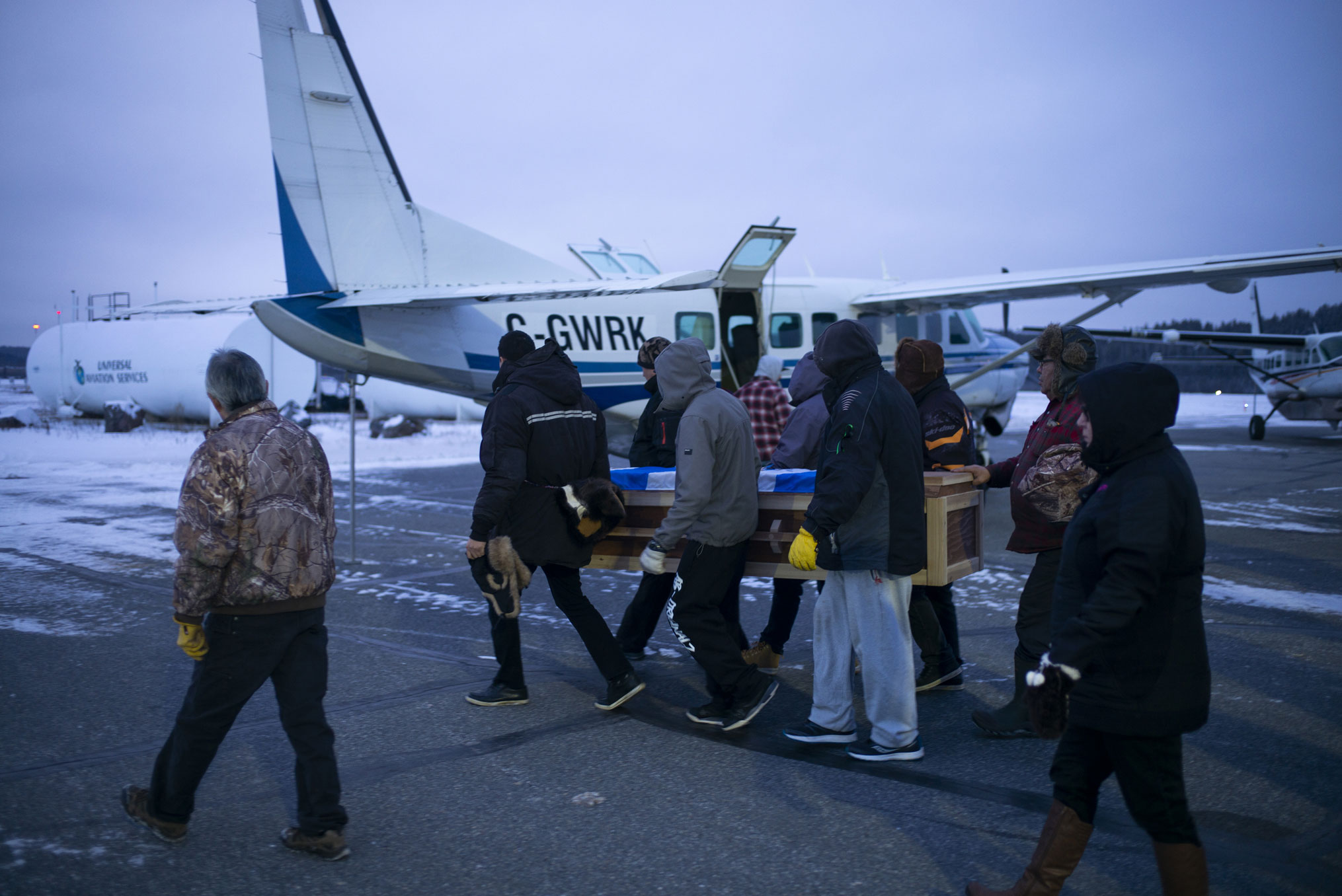 A casket is loaded onto a plane in the winter