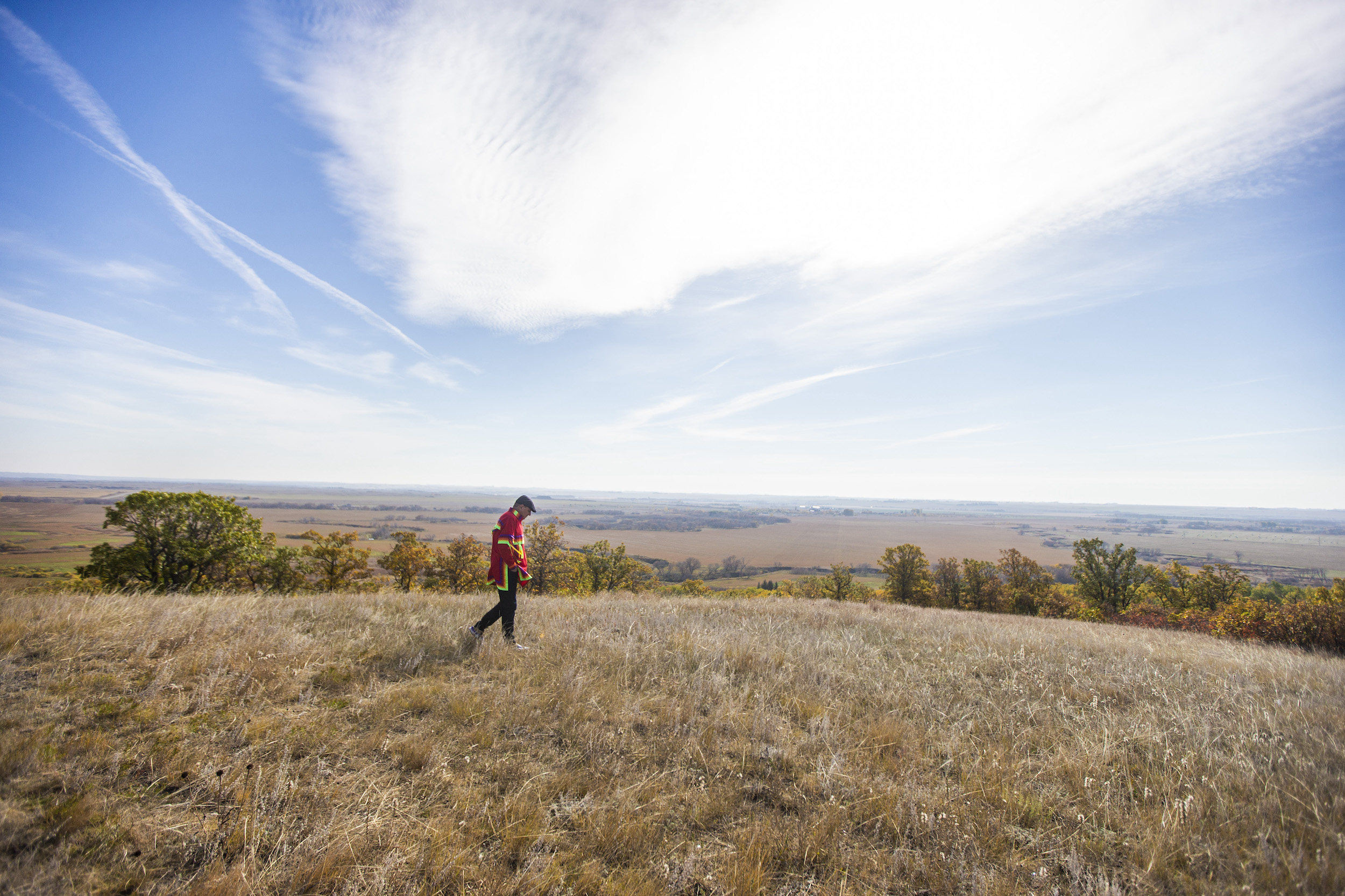 A man walks across the top of a hill in Sioux Valley, Manitoba