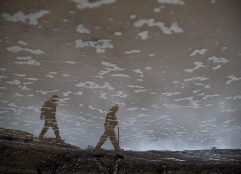 Two people walk along the muddy road that leads to the mouth of Hazeltine Creek.