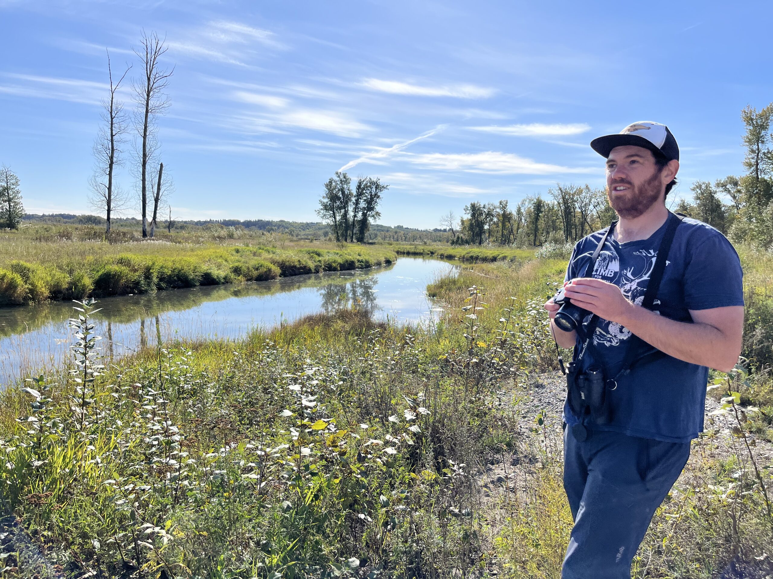 A man stands next to wetlands in Calgary