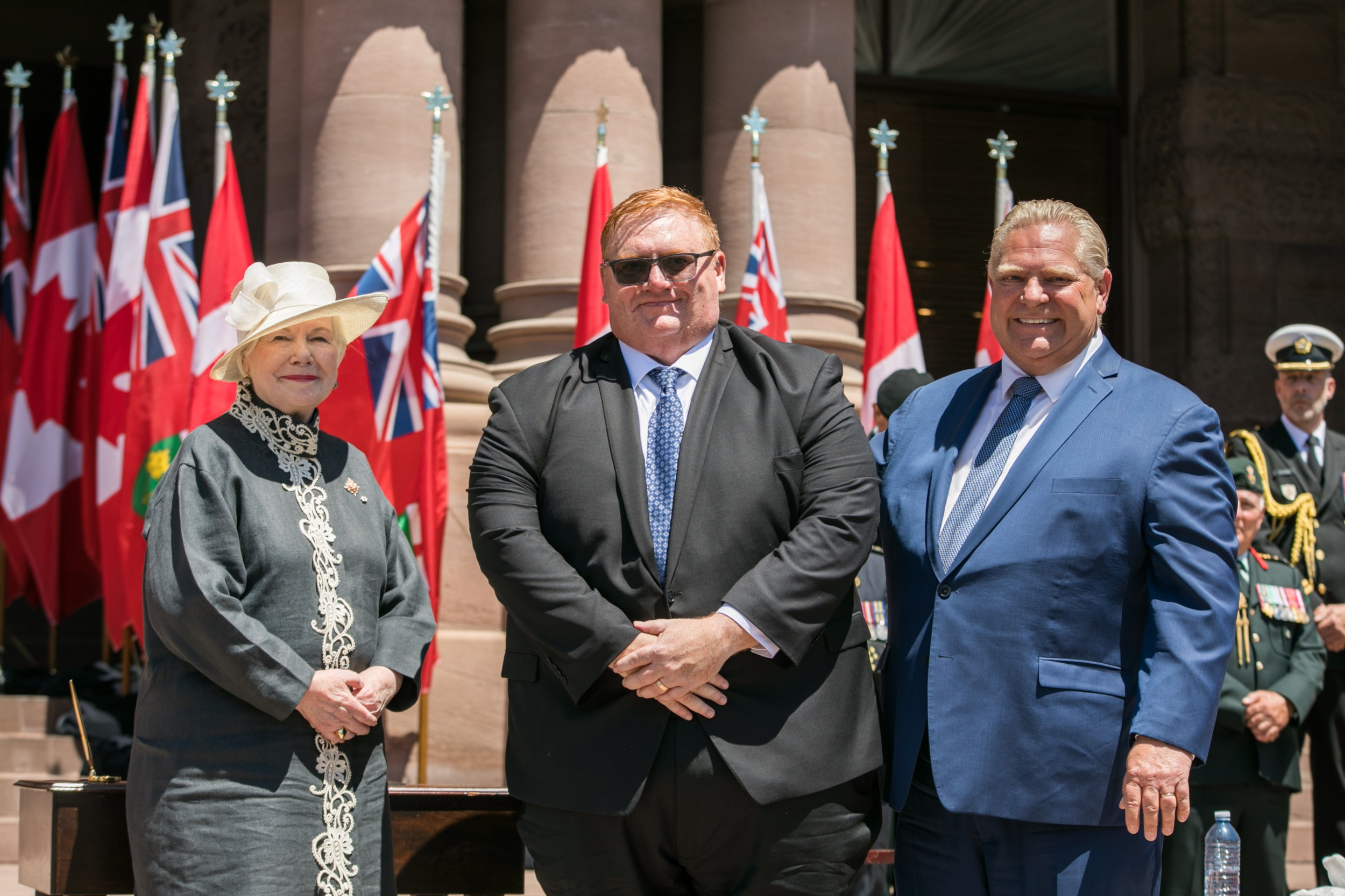 Ontario Natural Resources Minister Graydon Smith poses with a smiling Premier Doug Ford and Lt.-Gov. Elizabeth Dowdeswell in front of the legislature at Queen's Park.